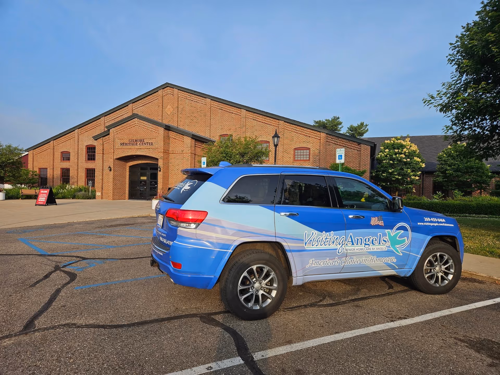 Visiting Angels vehicle parked in front of a brick senior living center.