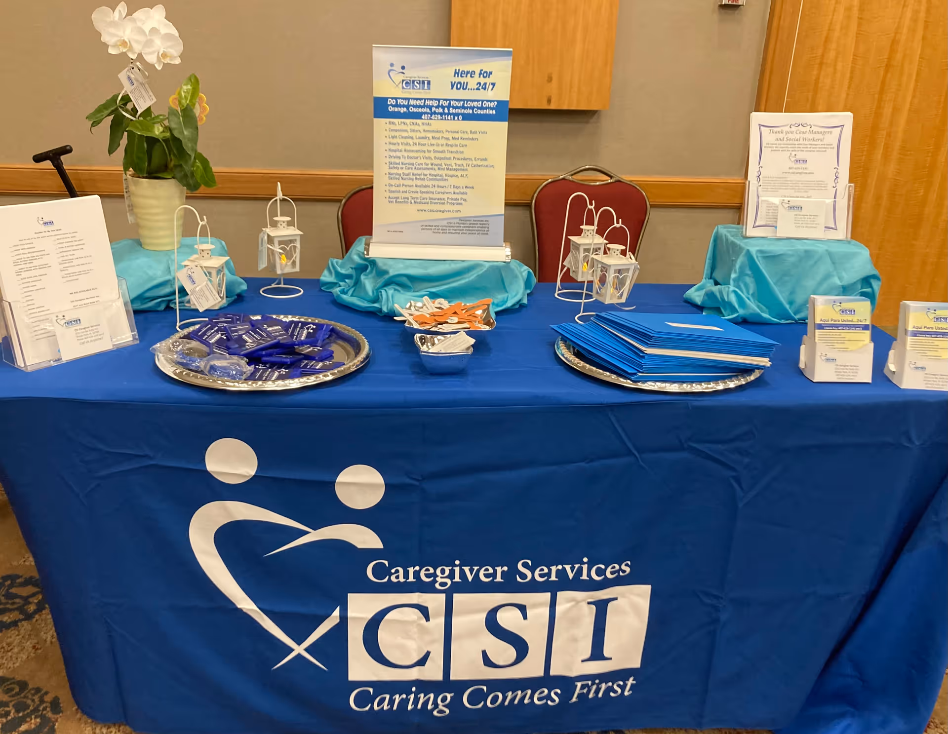 Indoor display table with blue tablecloth, CSI Caring Comes First banner, and brochures.