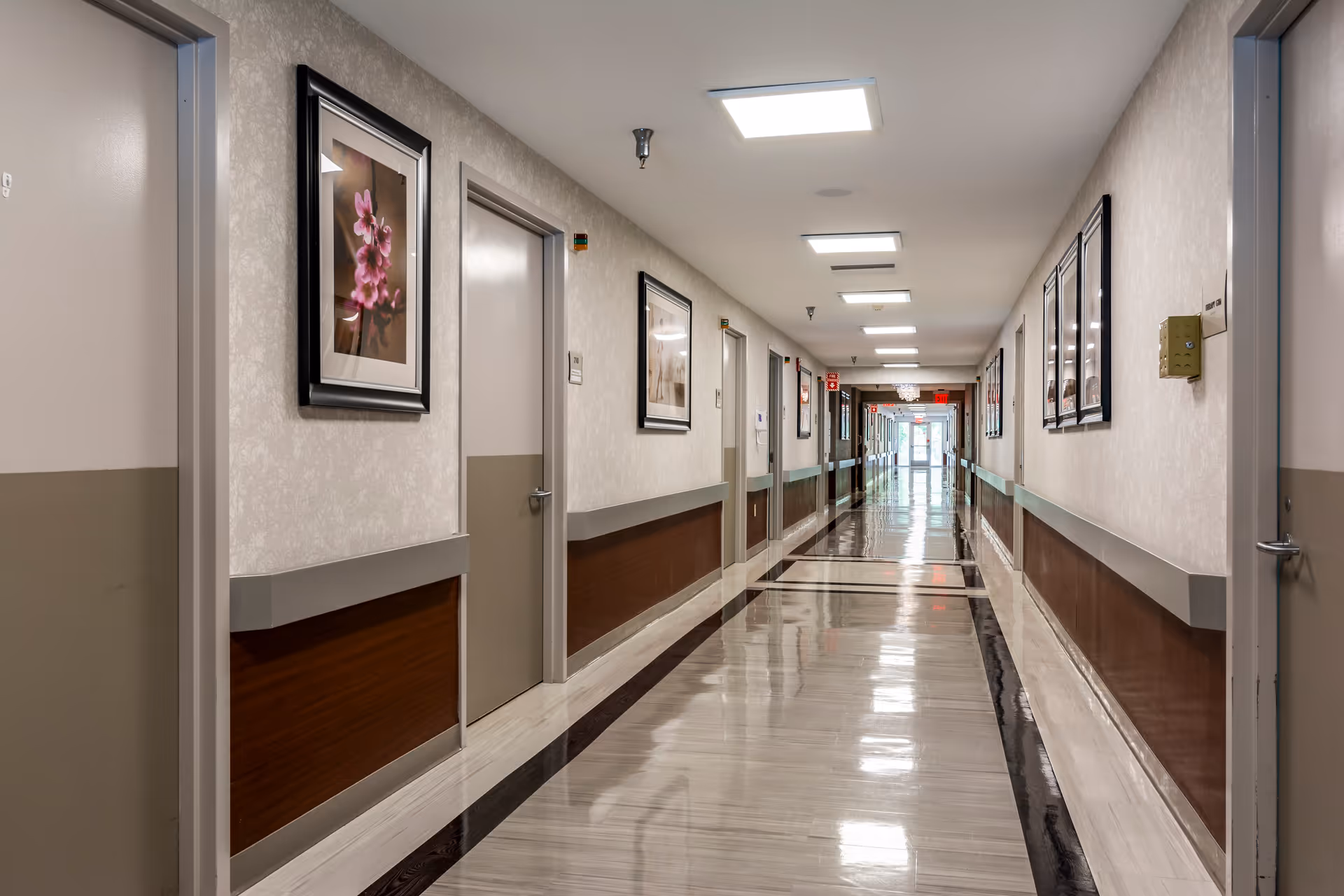Long interior hallway of a nursing center with framed wall art.