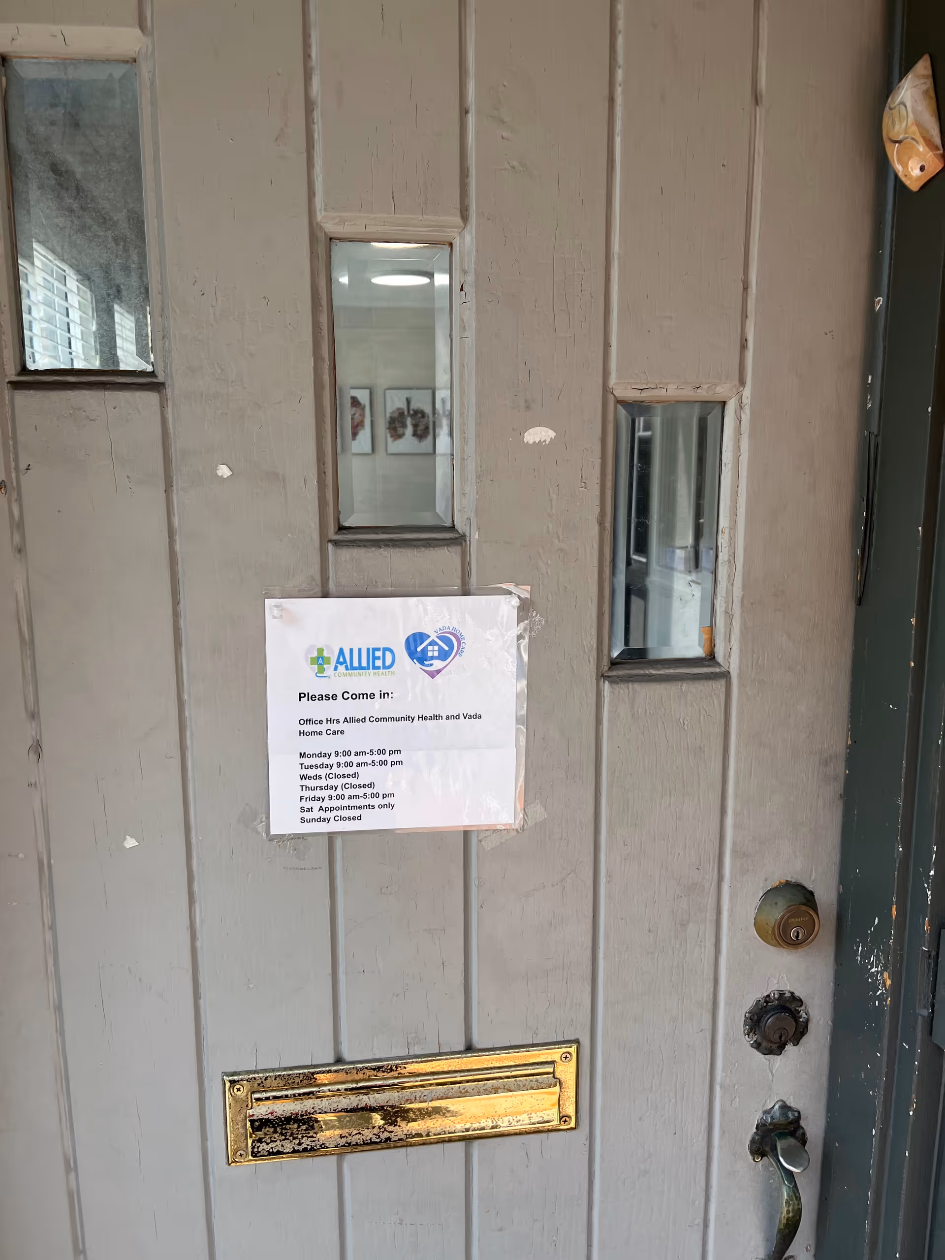 Weathered front door with posted hours for Allied Community Healthcare & Laboratory Services.