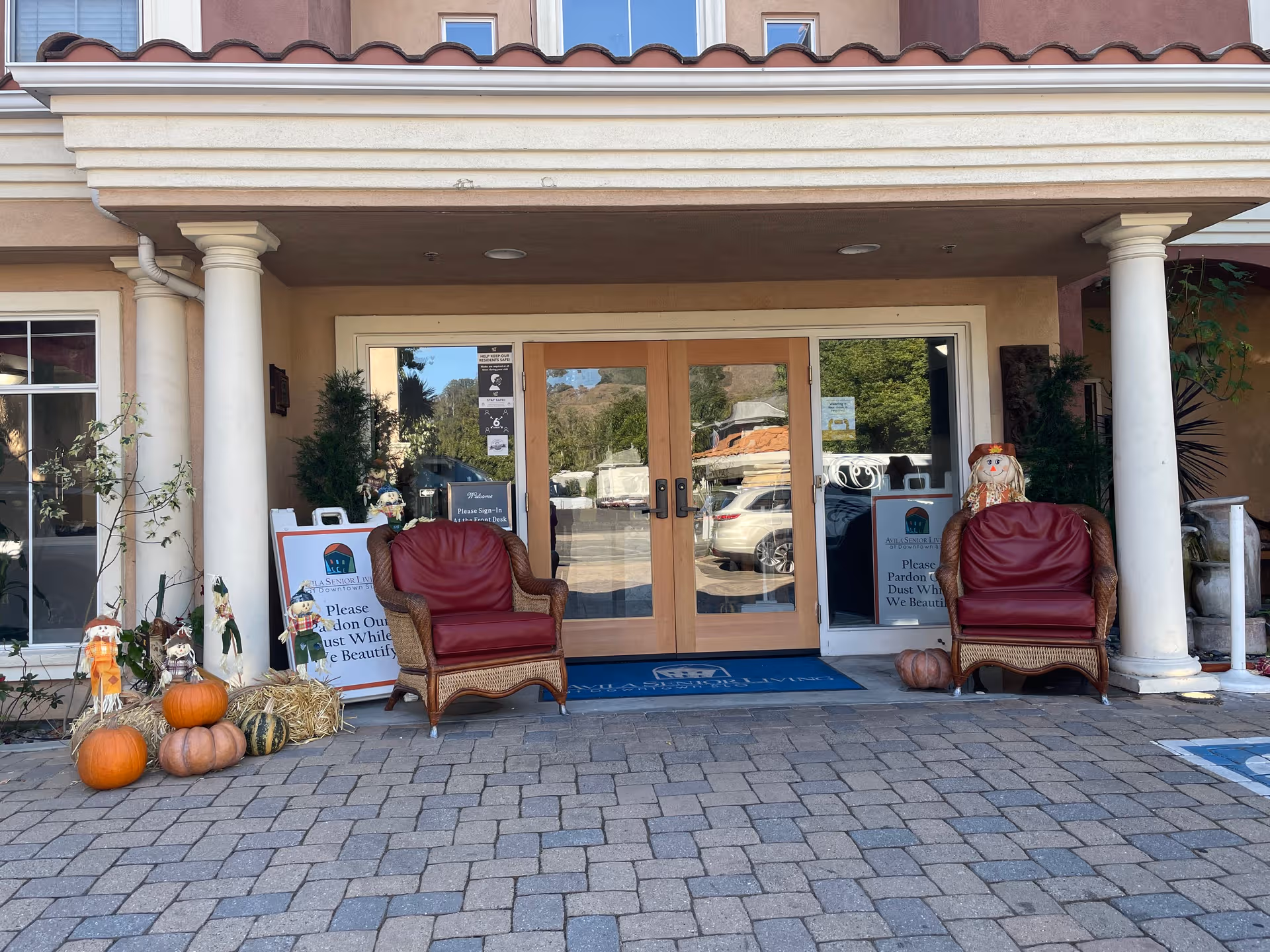 Entrance to Avila Senior Living Downtown SLO with wicker chairs and pumpkins