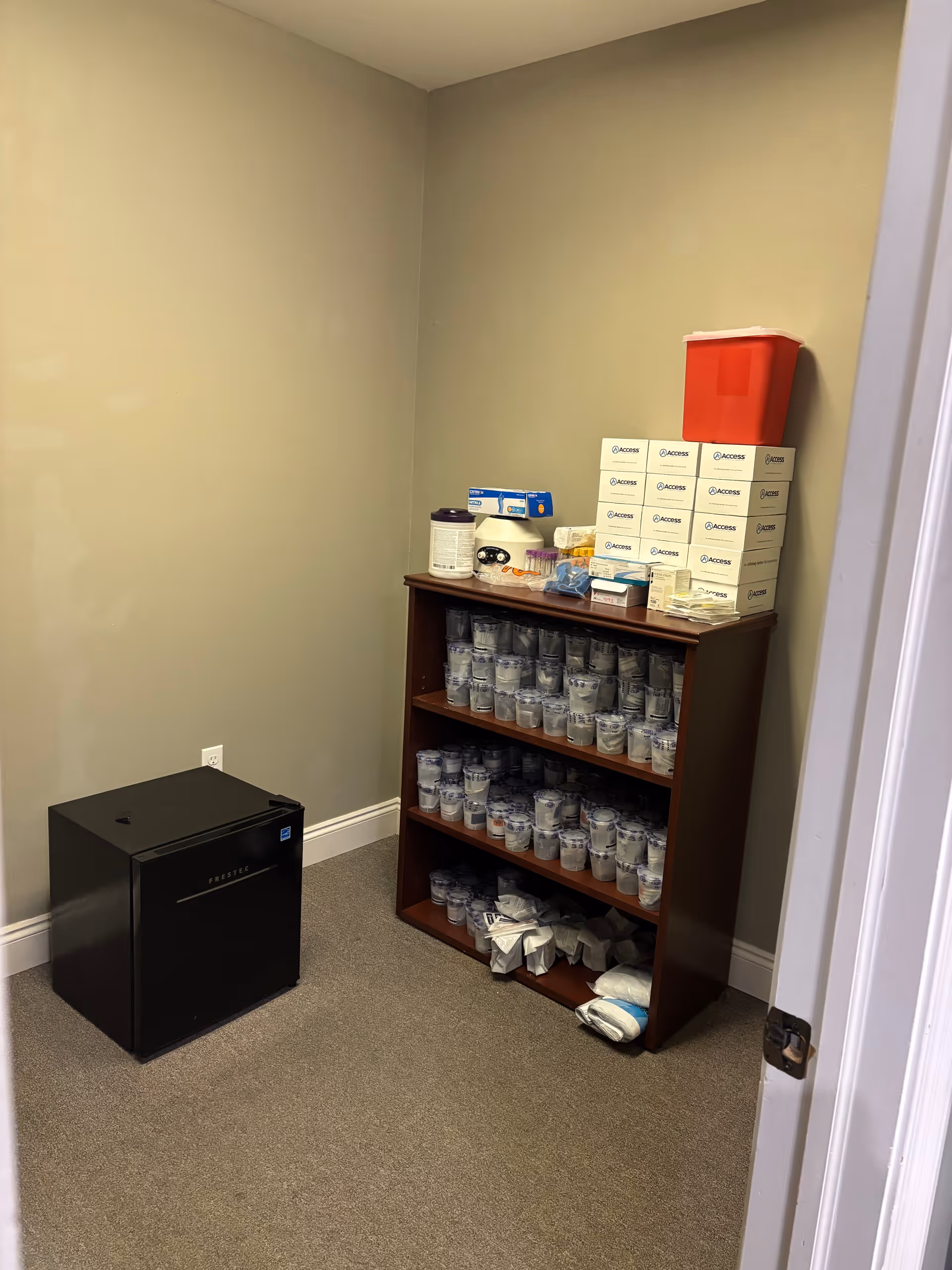 Small storage room with medicine boxes, cups, and a black safe on the floor.