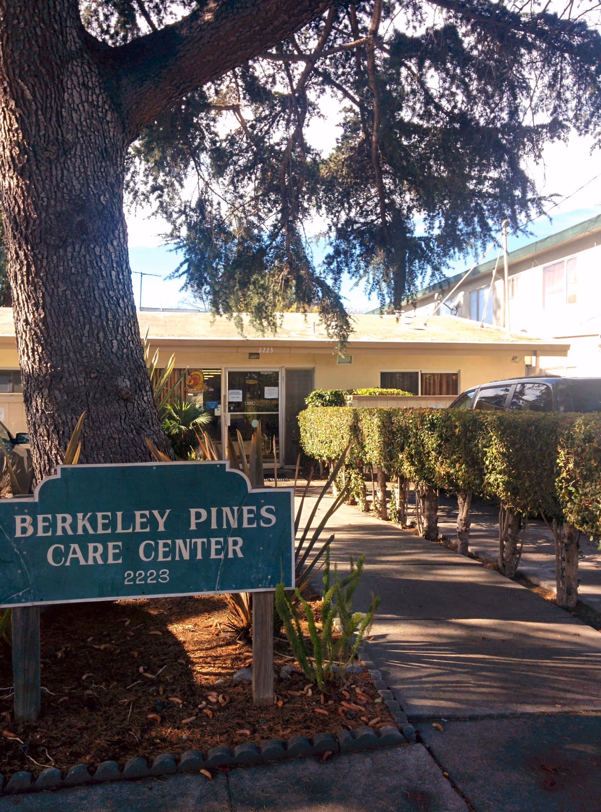 Exterior view of Berkeley Pines Care Center with a prominent sign and entry pathway.