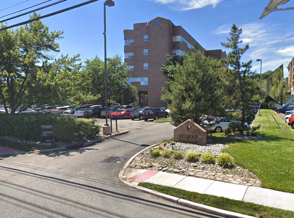 Exterior view of Complete Care at Regent building with parking lot and landscaping.