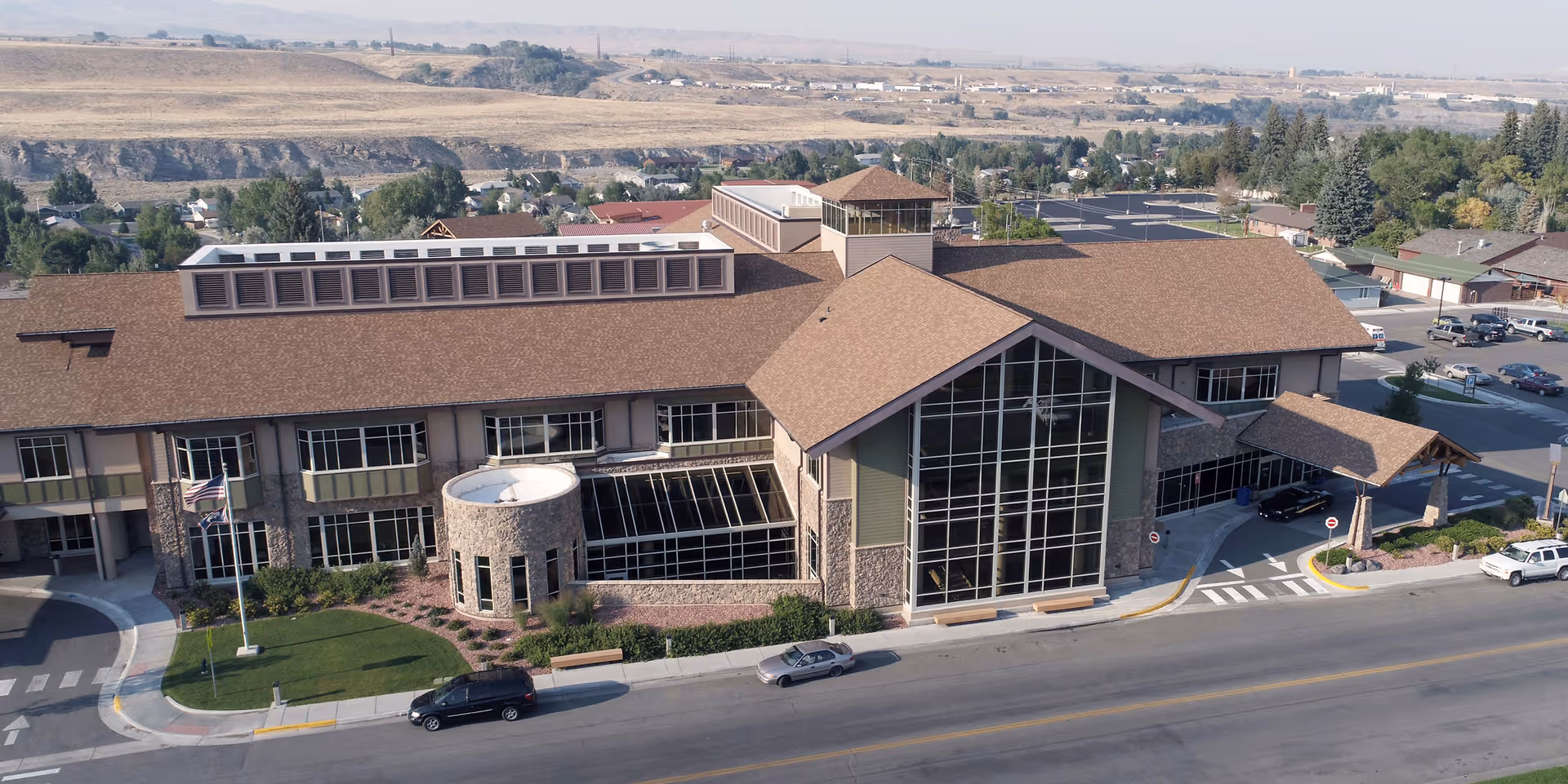 Exterior of a modern senior living facility with a glass entrance and parking