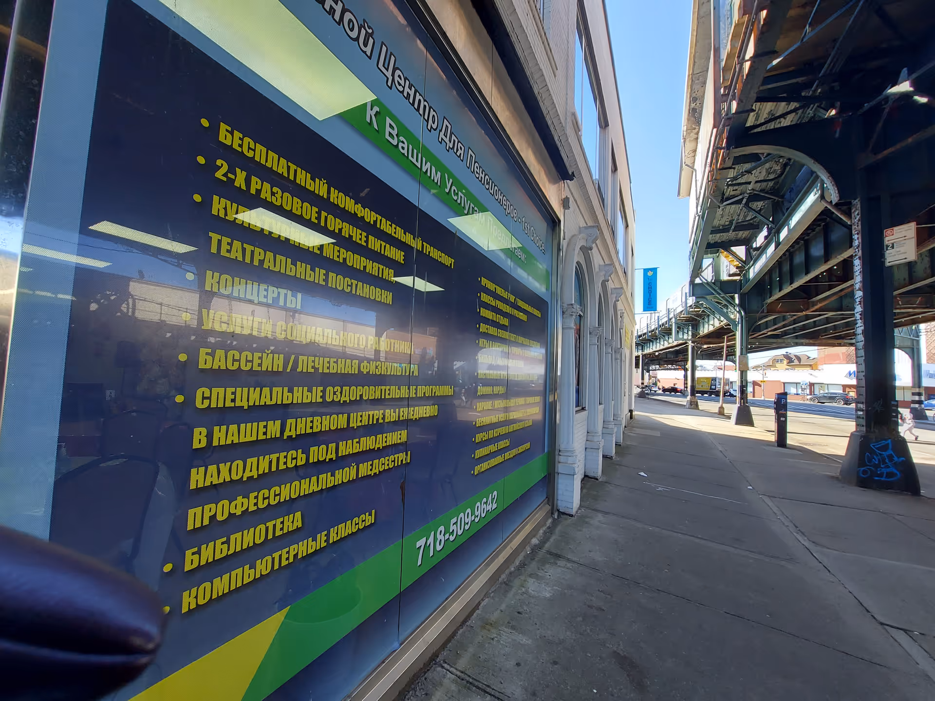 Street view of a building storefront with a large blue sign covered in yellow Cyrillic text.