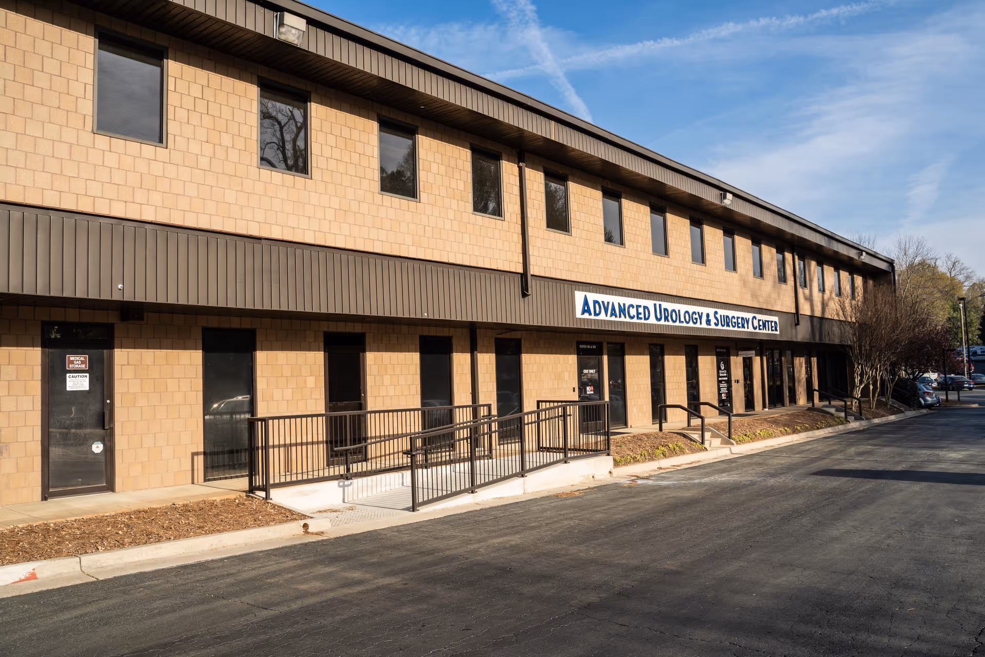 Two-story brick medical building with accessible ramp and a blue Advanced Urology & Surgery Center sign.