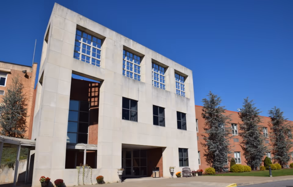 Front exterior of a modern senior living building with large windows and blue sky.