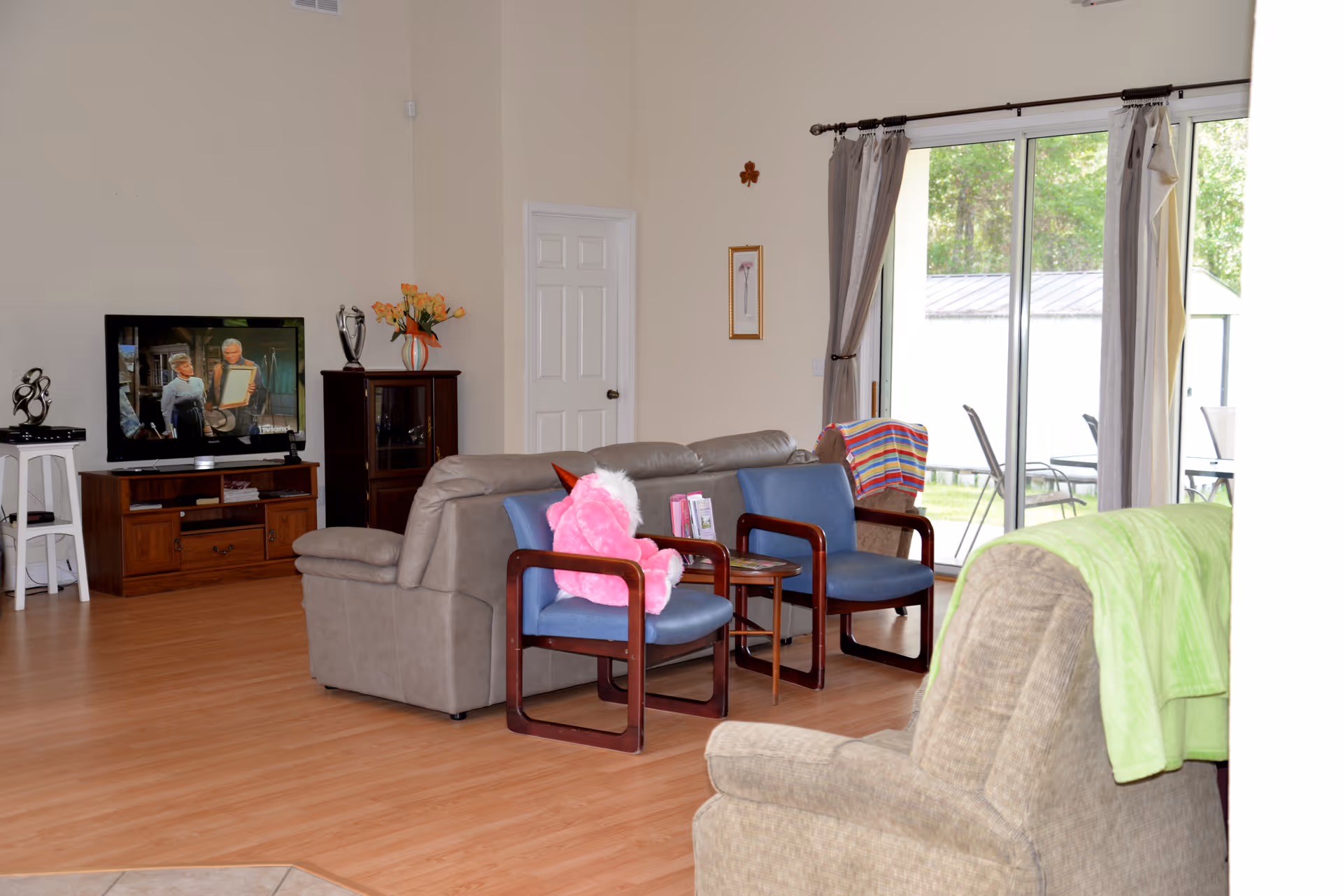 Living room with sofa, chairs, TV, and sliding glass doors to the outdoors.