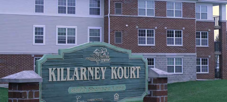 Exterior view of Killarney Kourt facility with a green sign in front of the building.
