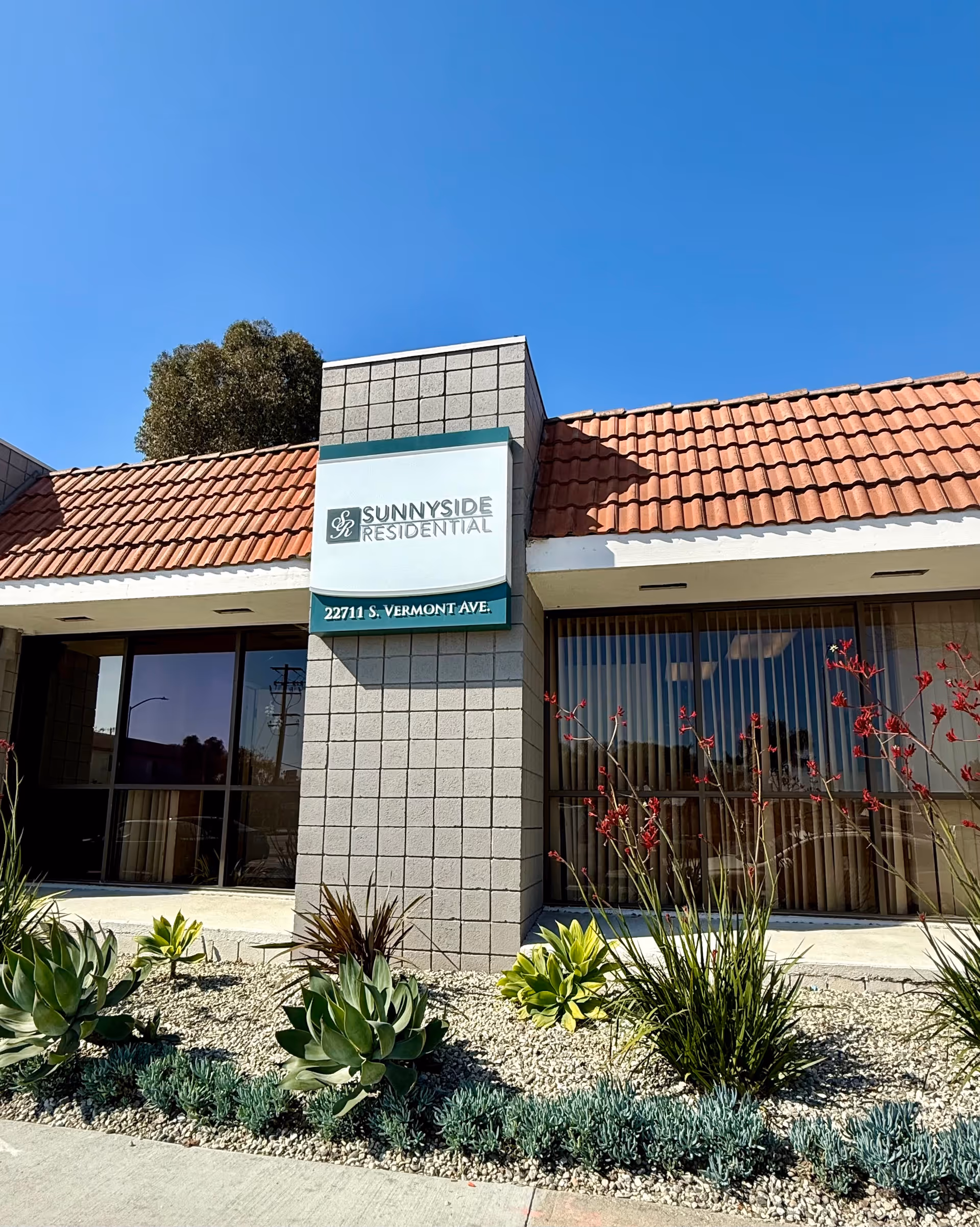 Exterior view of Sunnyside Residential building with desert landscaping and a red-tiled roof.