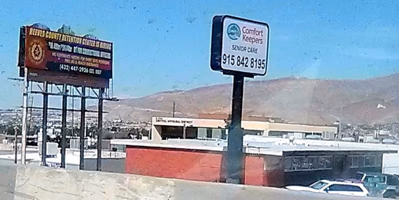 Front exterior view with Comfort Keepers Senior Care sign and desert mountains in background.