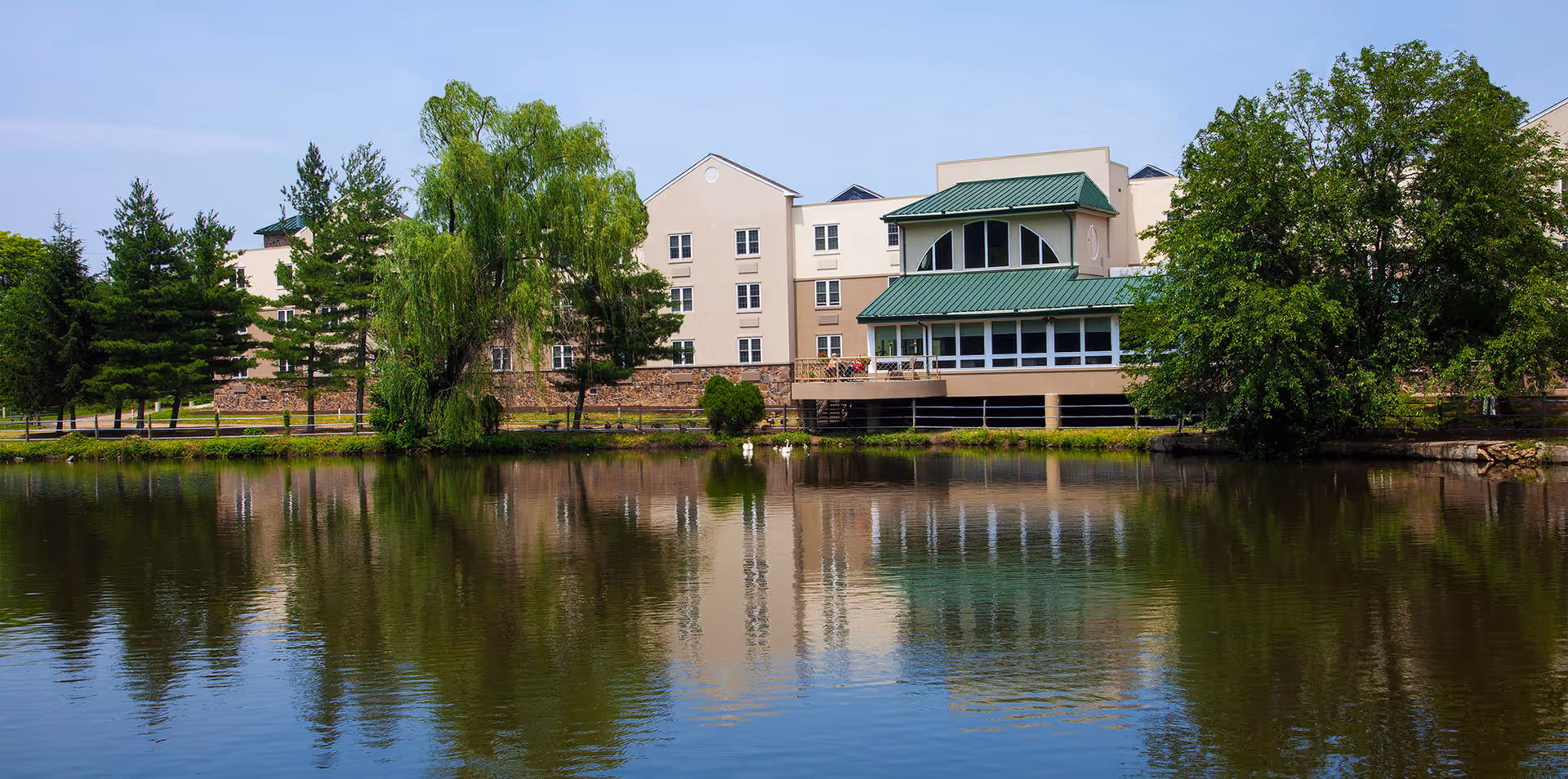 Exterior view of Commonwealth Senior Living at Willow Grove beside a calm lake