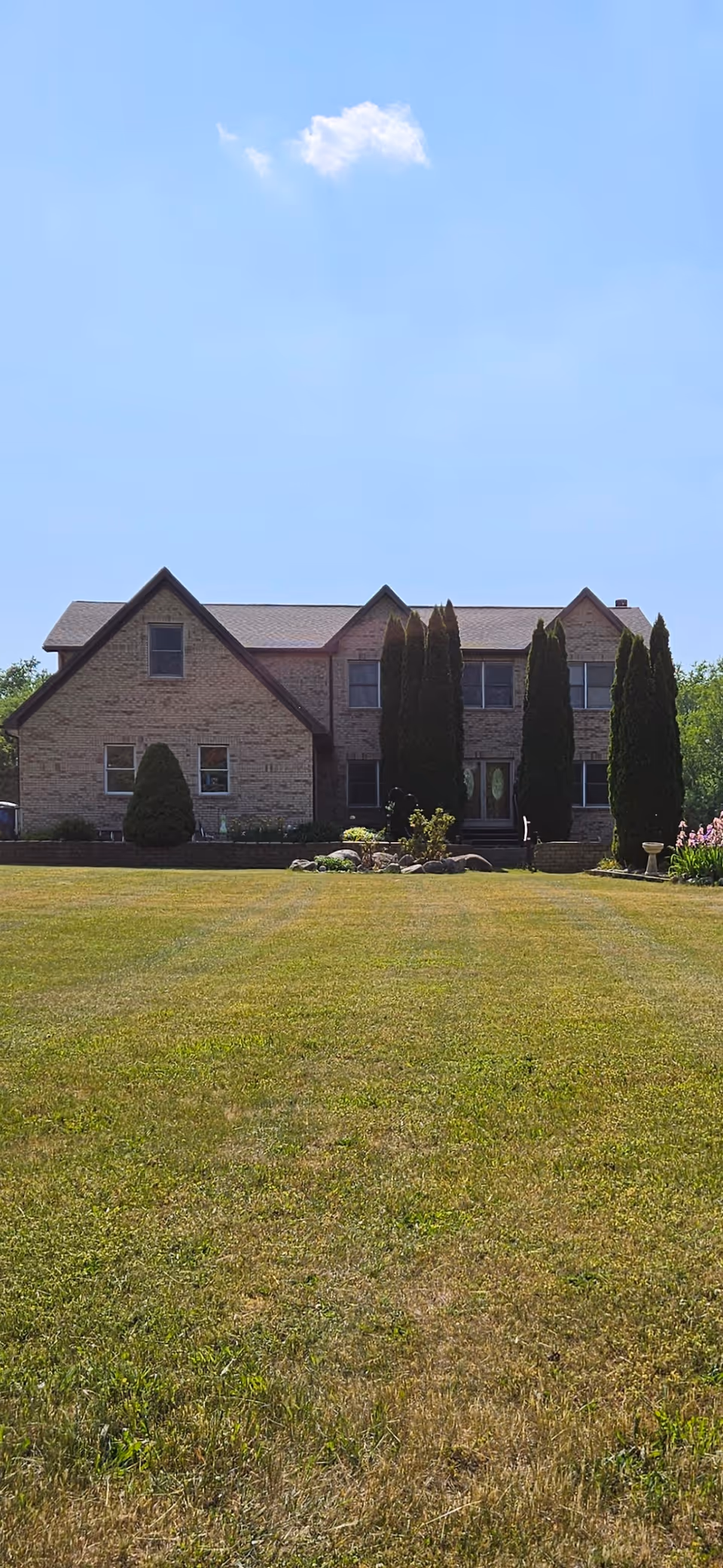 Brick two-story building with manicured lawn and tall trees in front.