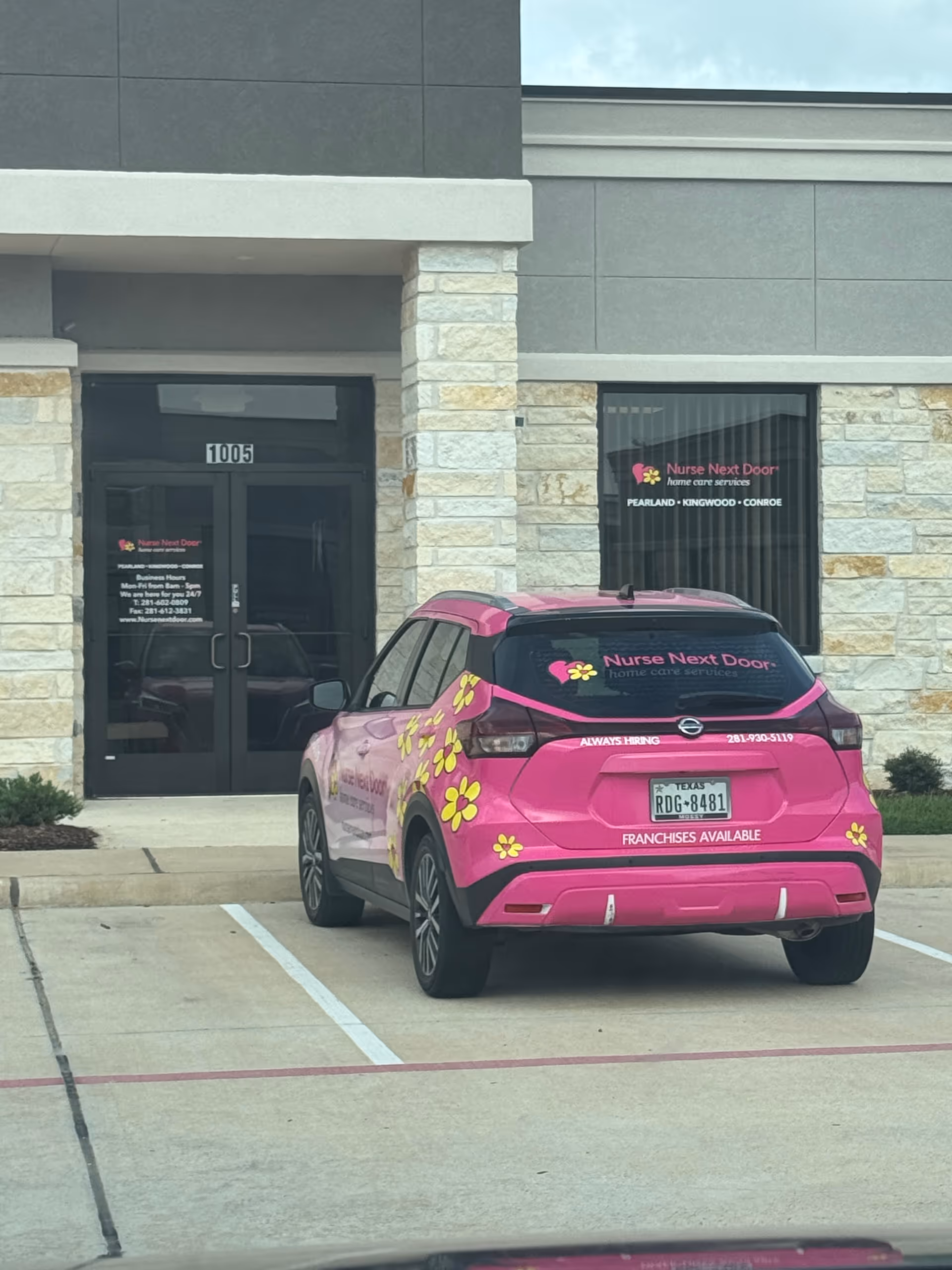 Pink Nurse Next Door car parked in front of a modern senior care facility.