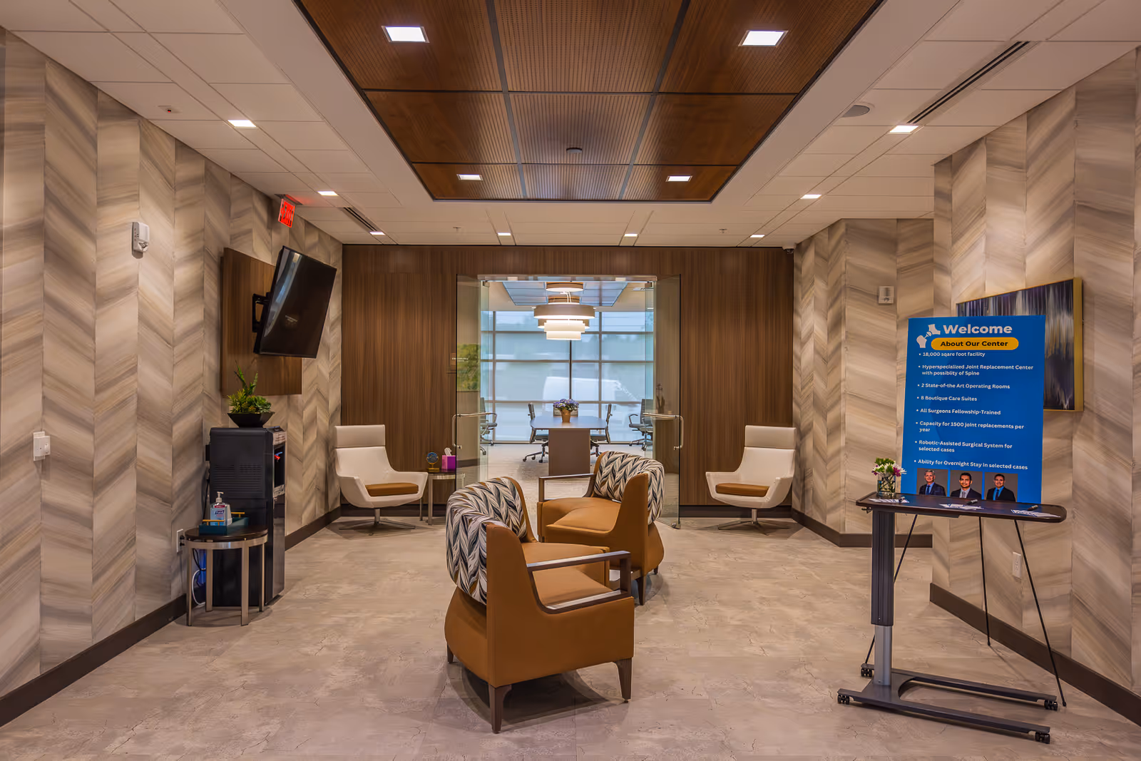 Modern hospital-style lobby in a senior living facility with seating, plants, and glass doors.