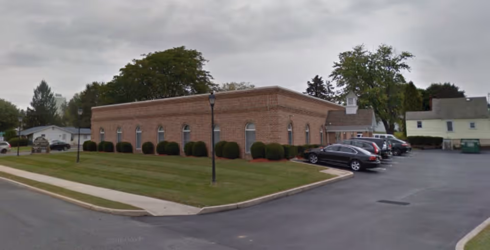 Exterior view of APlus United Home Care brick facility with a parking lot and lawn.