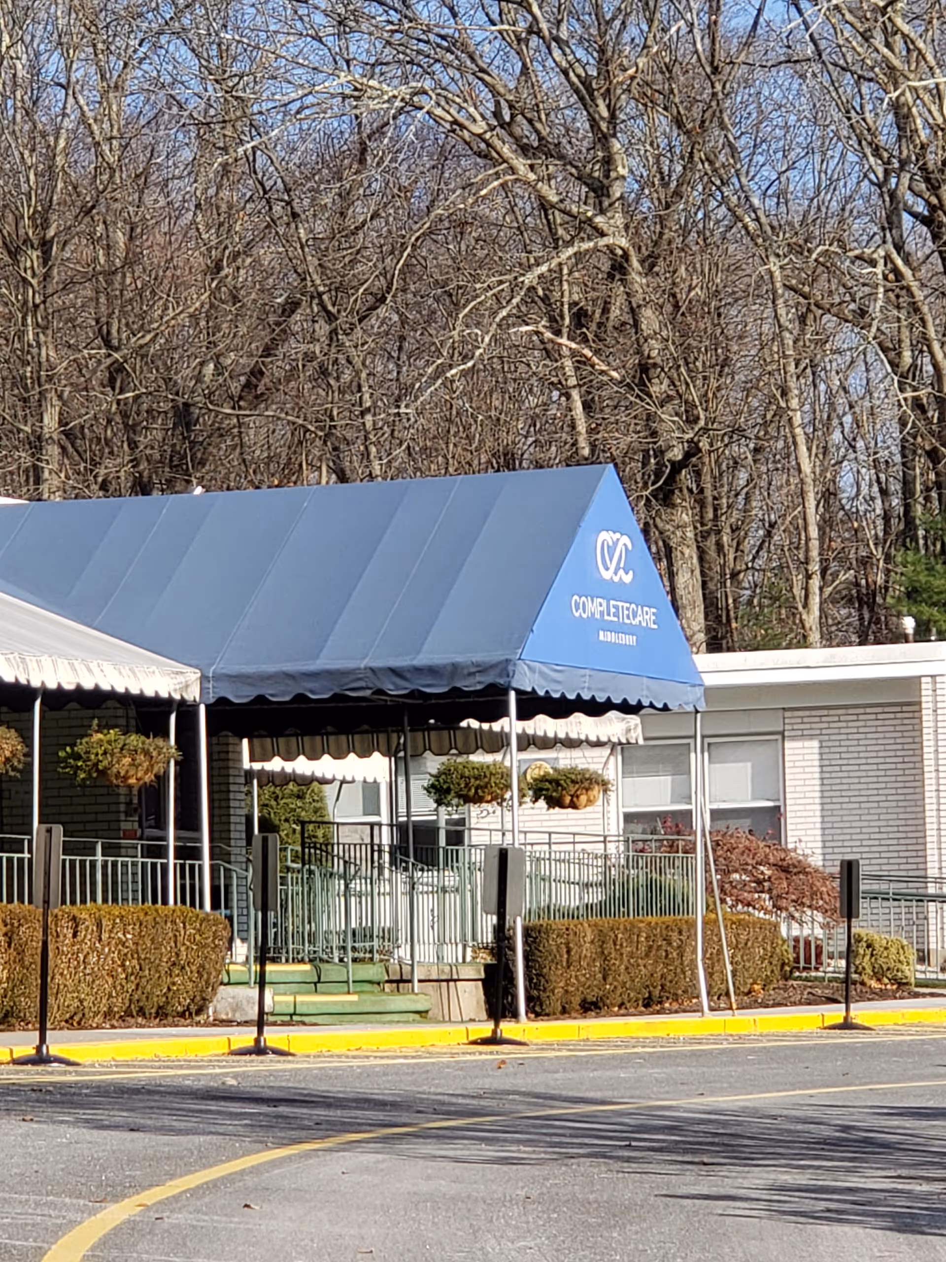 Blue canopy with Complete Care signage covers the facility entrance in a small parking area.