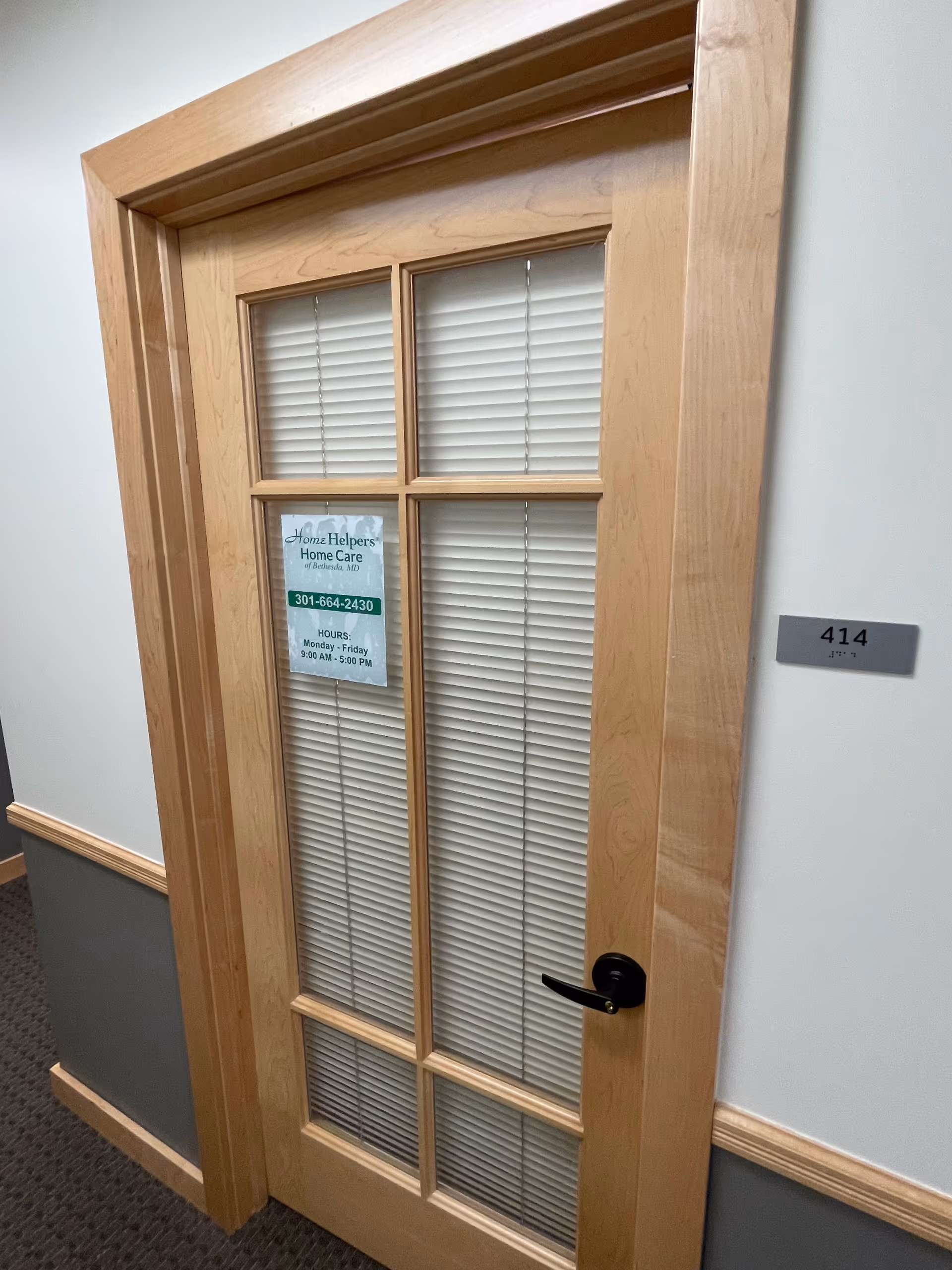 Wood-framed glass door in a hallway with blinds and a Home Helpers sign