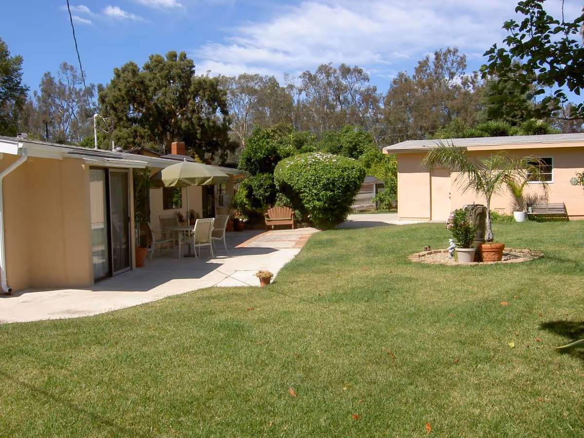 Outdoor view at Villa Blanca with patio furniture, an umbrella, and a manicured lawn.