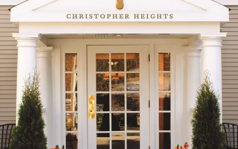 Entrance to Christopher Heights Worcester with double doors, columns, and greenery.
