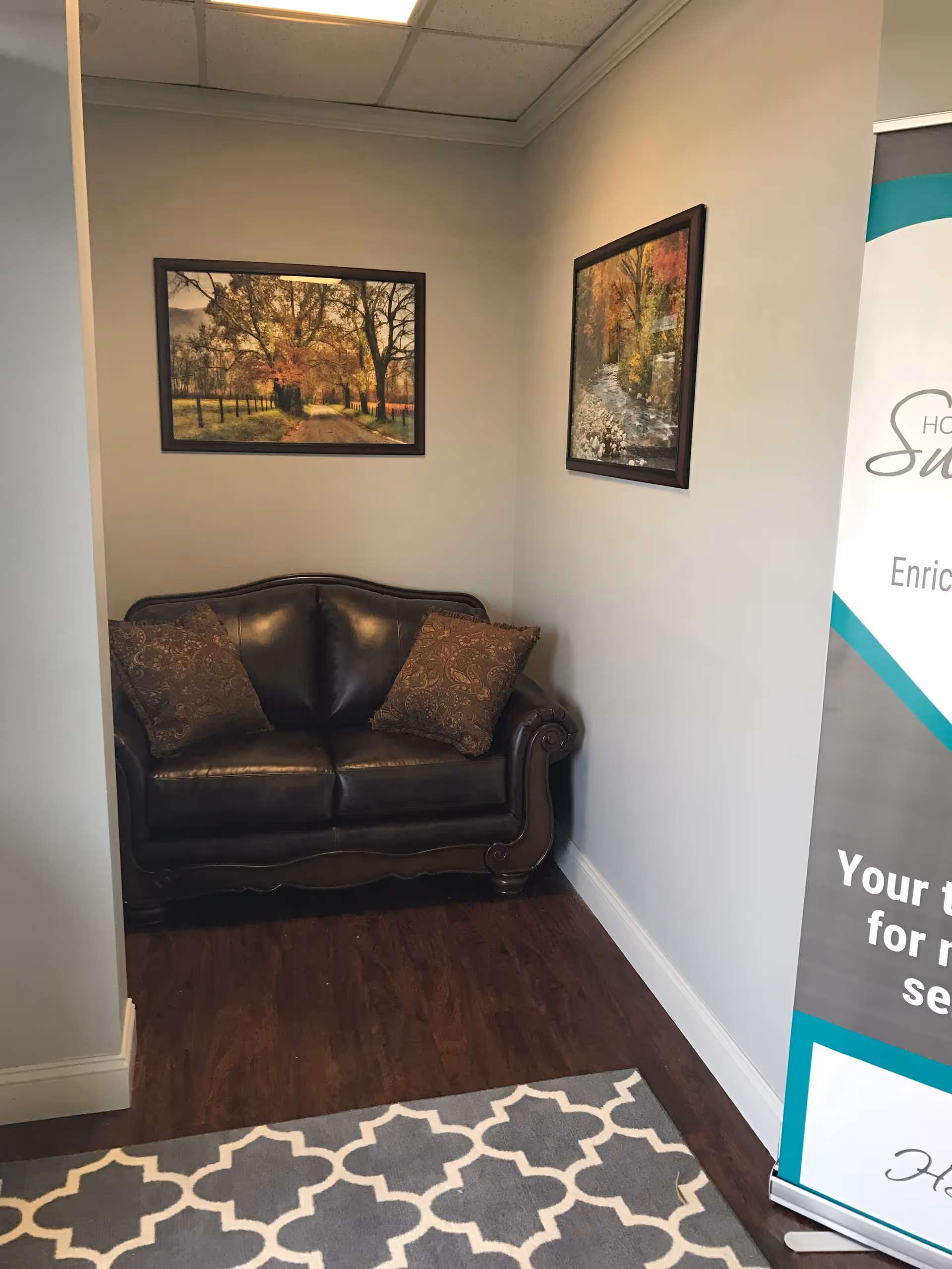 A dark leather sofa with two decorative pillows sits in a small lounge area.