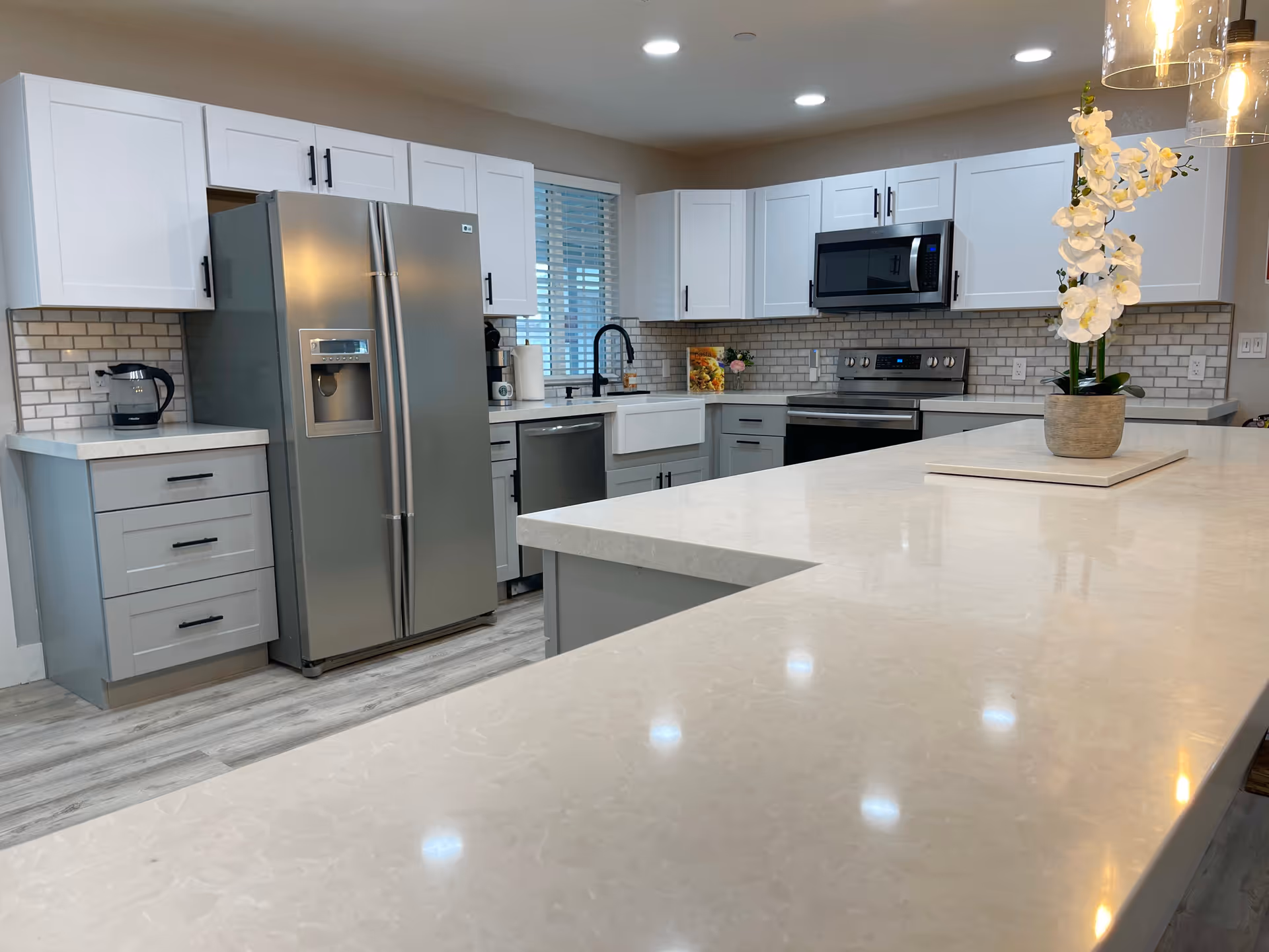 Bright modern kitchen with white cabinets, stainless appliances, and a large island.