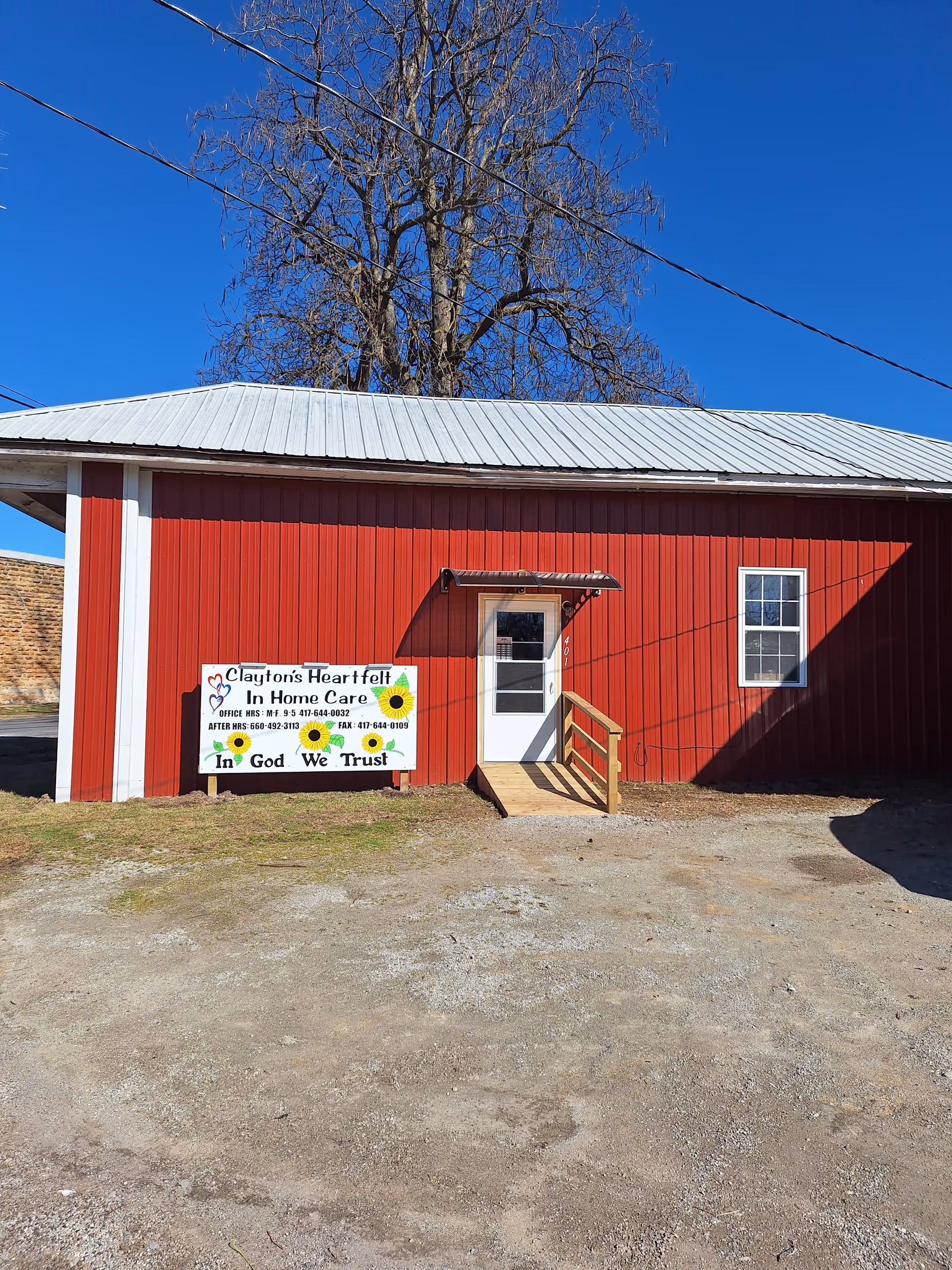 Red metal building with a white door and a sign reading Clayton's Heartfelt In Home Care.