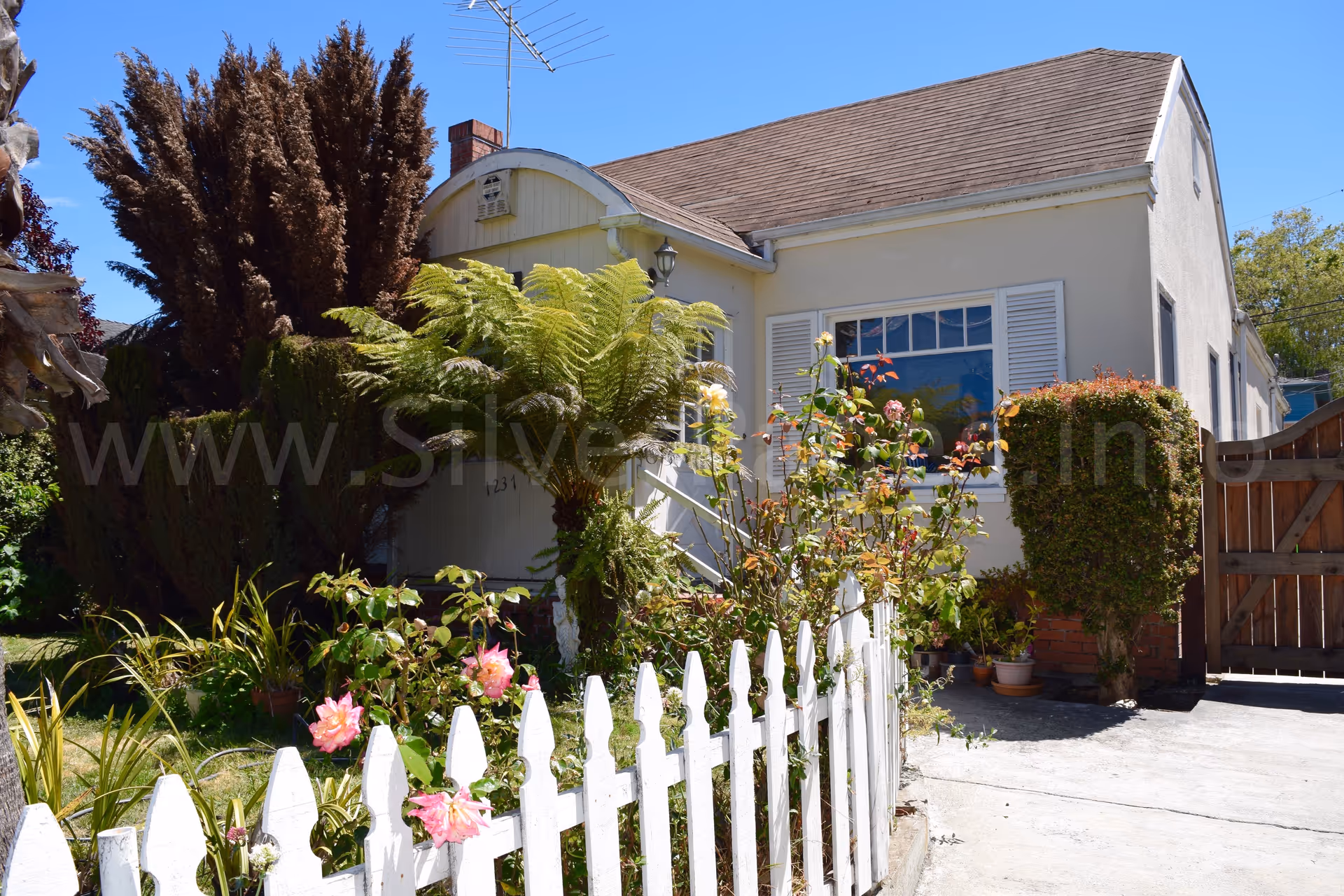 Front view of Burlingame Senior Home with white picket fence and lush garden.