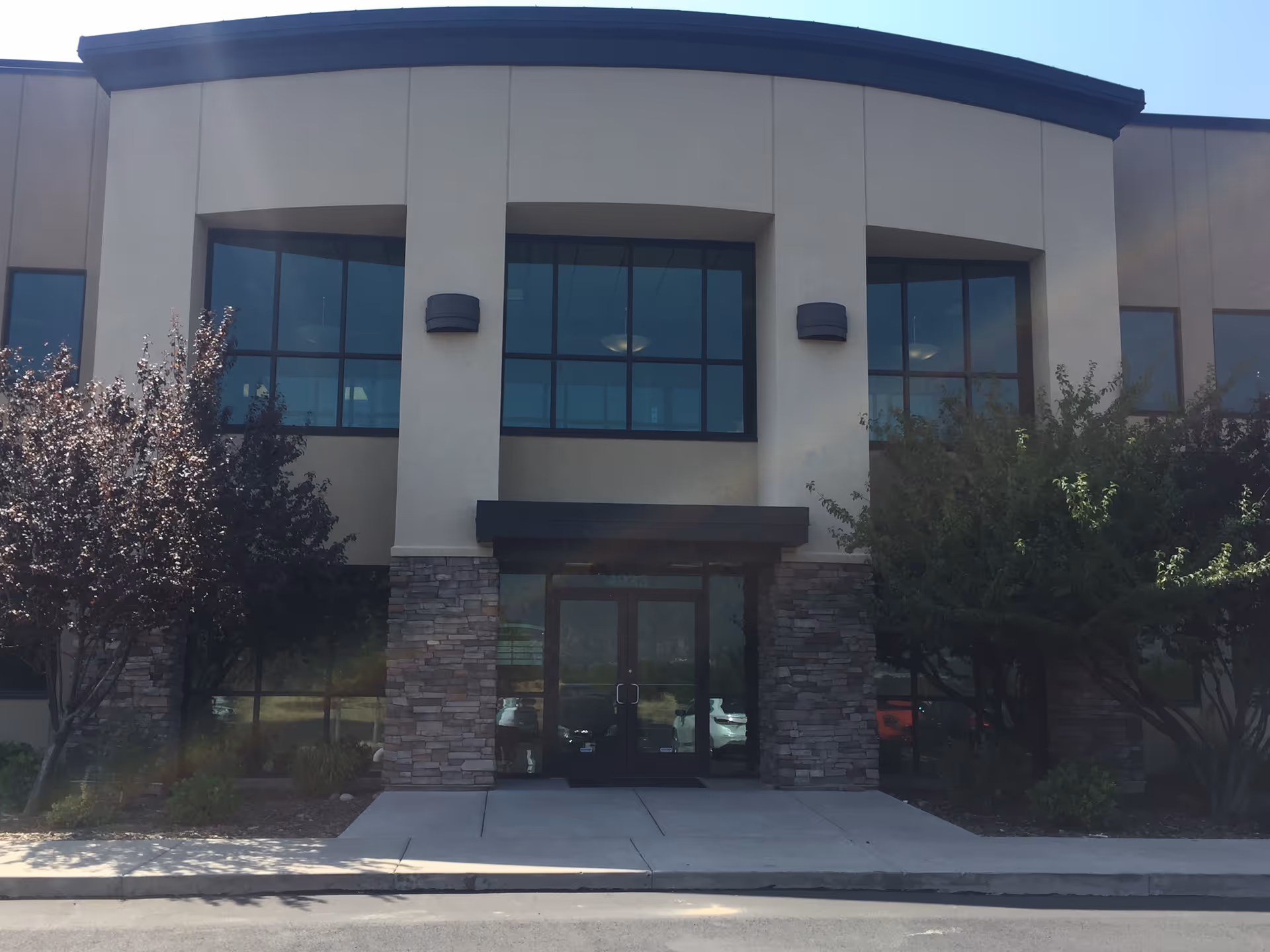 Exterior view of a modern facility entrance with glass windows and stone accents.