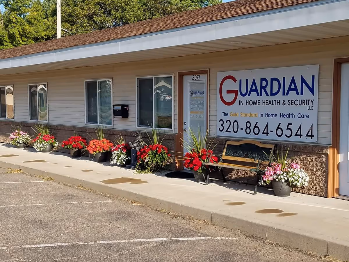 Exterior view of Guardian In Home Health Security building with colorful flower planters and sign.