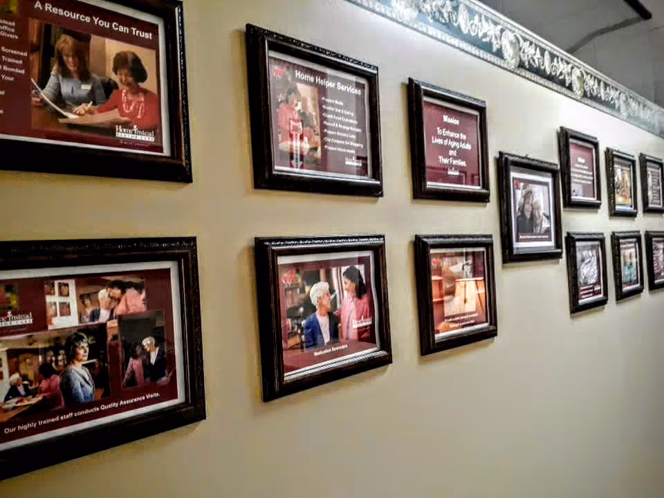 Hallway wall lined with framed photos and posters in a senior facility corridor.