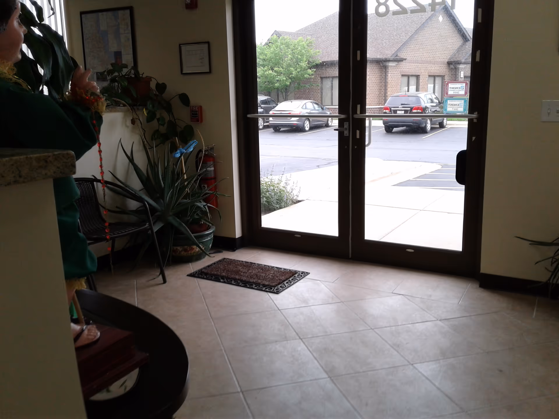 Lobby area with glass front doors, potted plants, and a person on the left.