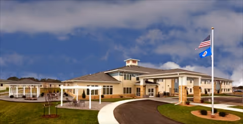 Exterior view of a Benedictine senior living facility with a curved entrance and flags.