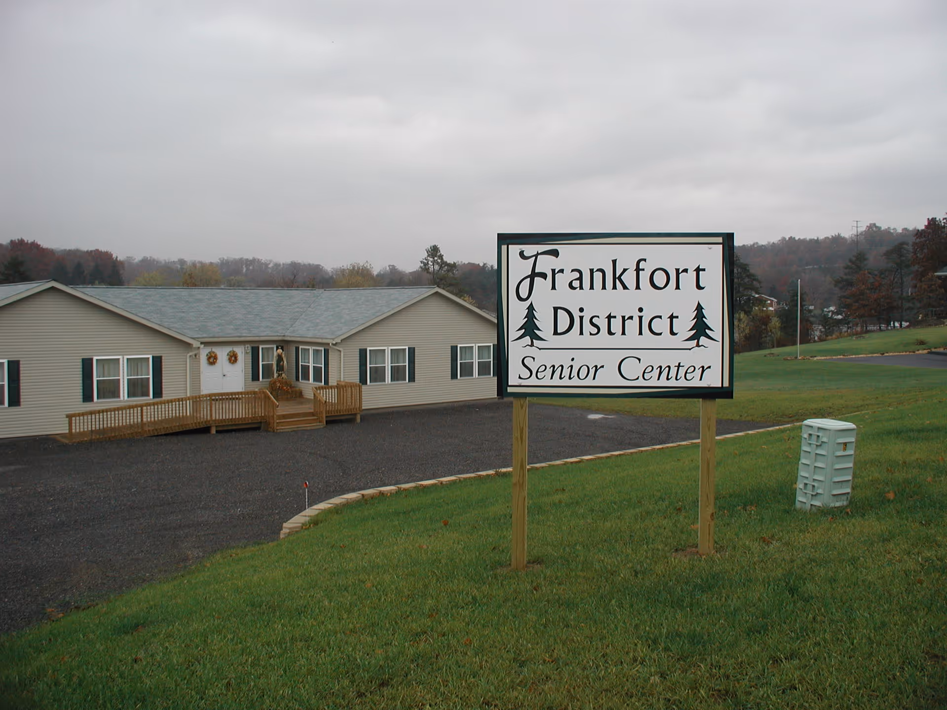 Exterior view of a single-story senior center with a sign in the grassy foreground.