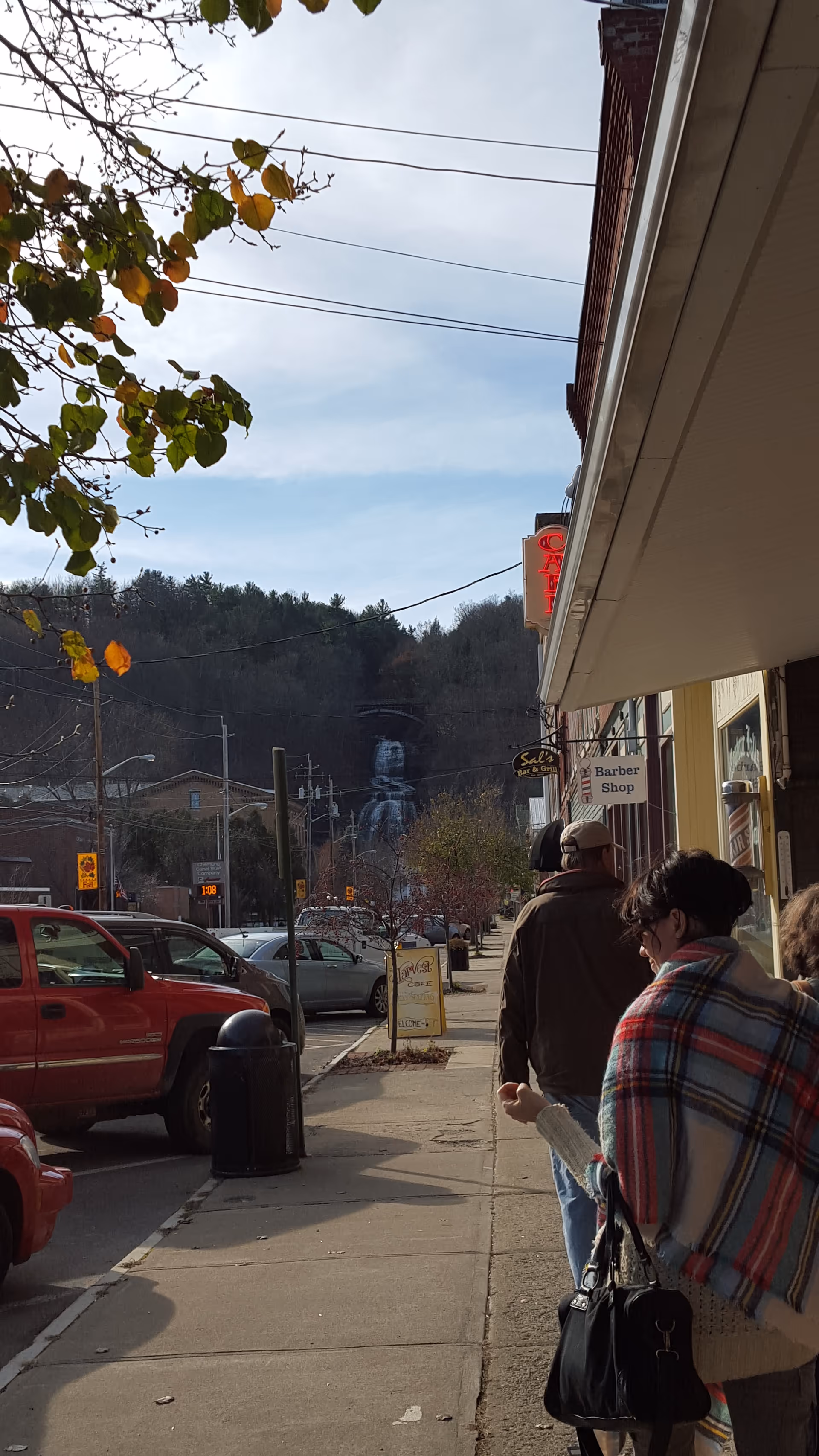 Sidewalk view of storefronts with people walking along a street and an awning.