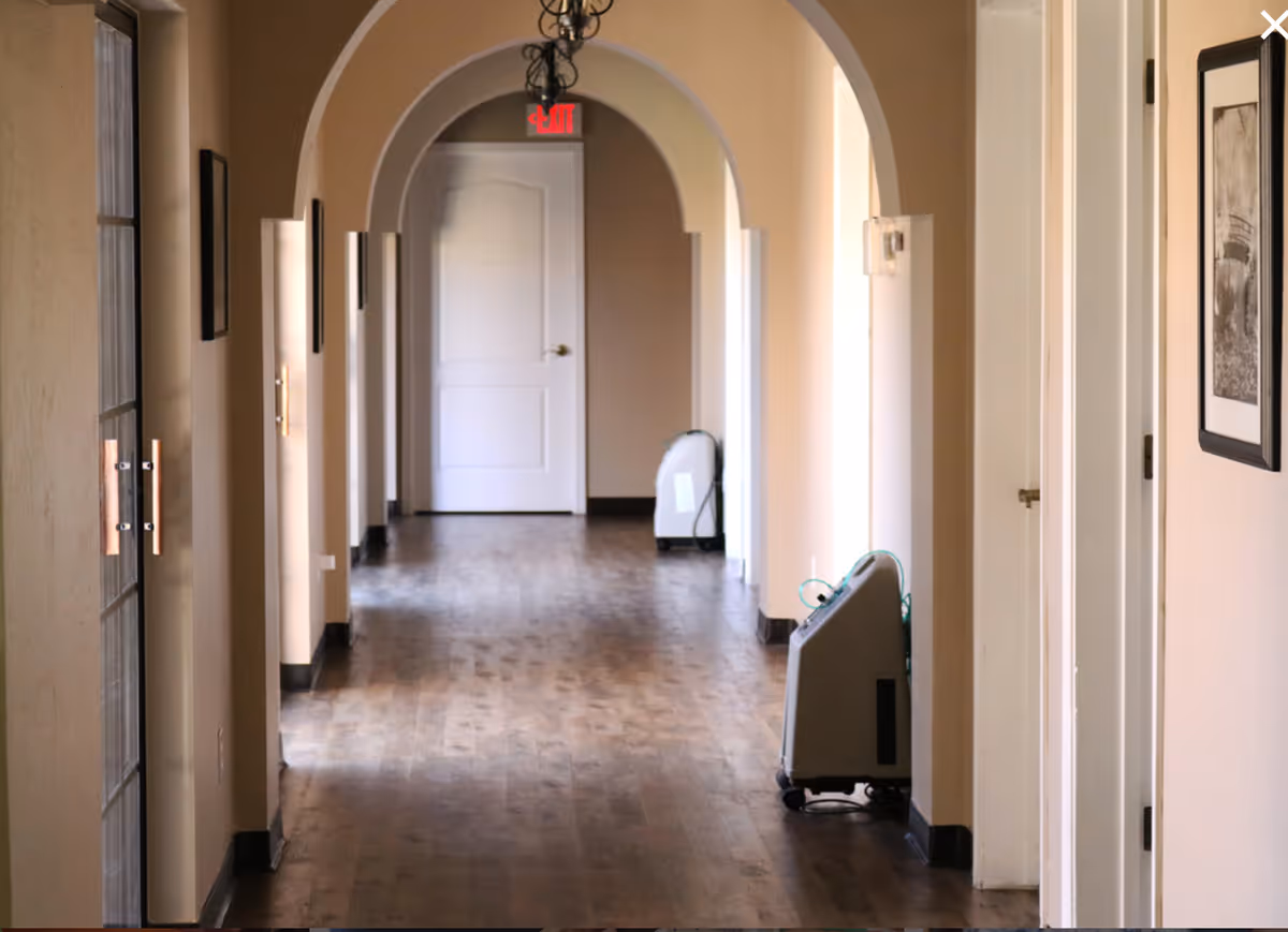 Long arched hallway in an assisted living facility with doors and equipment along sides.