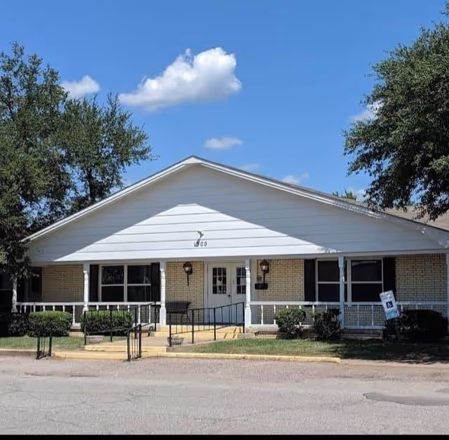 Front view of a single-story senior living facility with a welcoming porch and entrance.