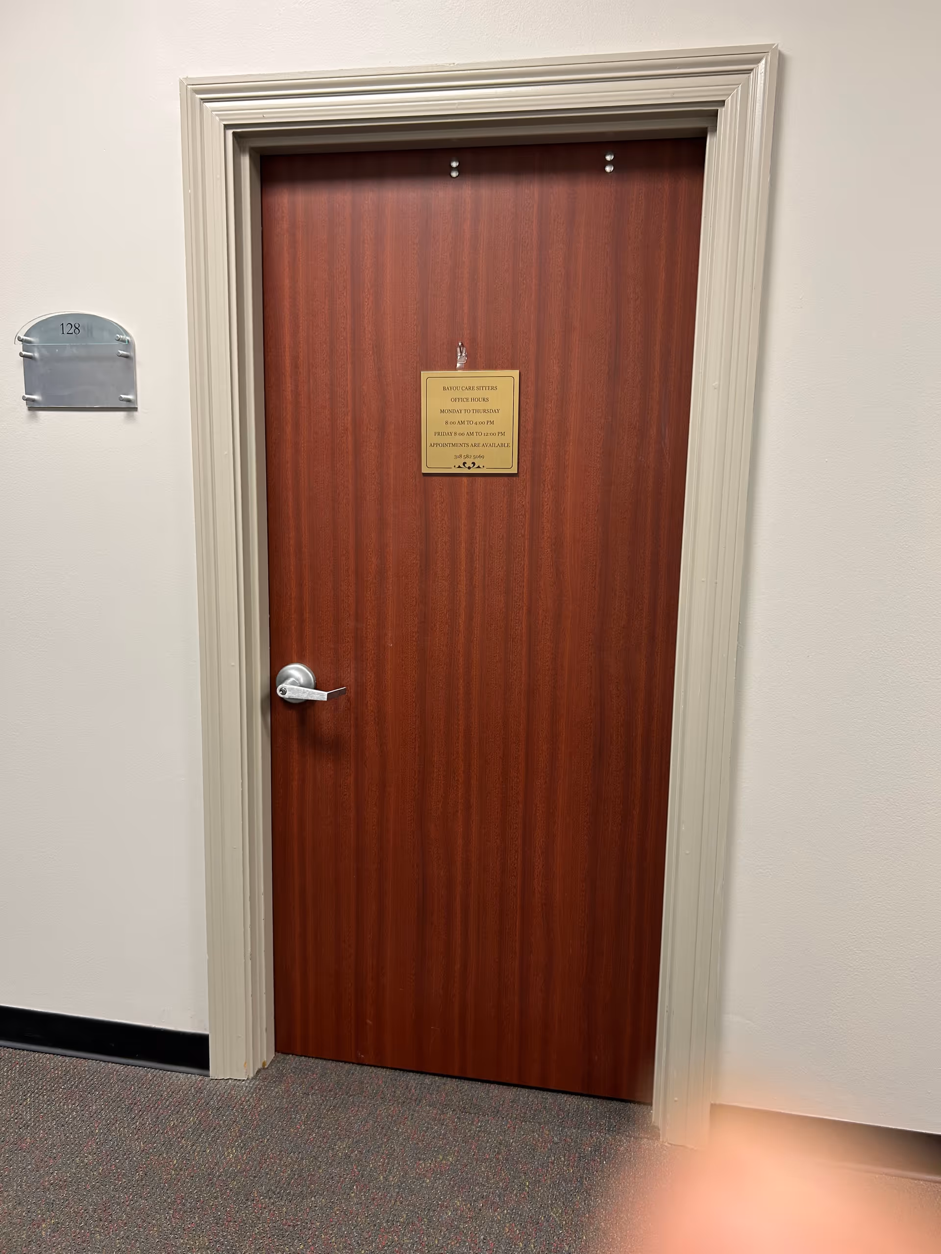 Wooden interior door in a hallway with a small plaque and left mailbox.