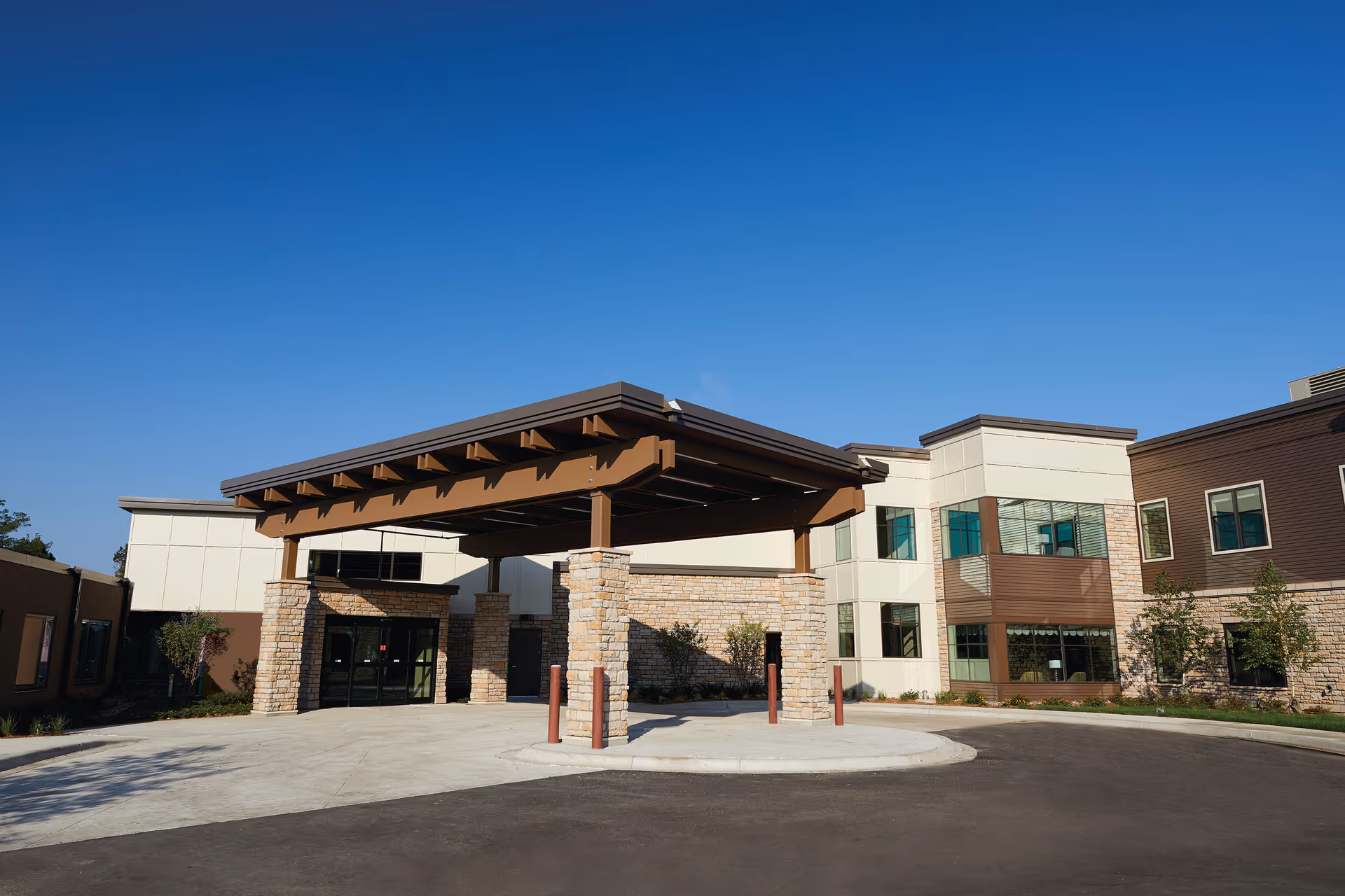 Modern senior living facility exterior featuring a stone entrance and blue sky