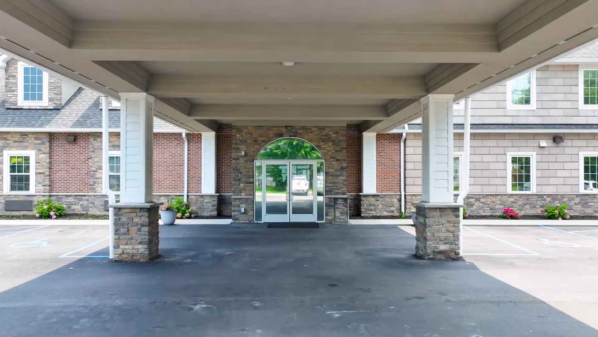 Covered entrance to Meadows Assisted Living I with brick and stone exterior.