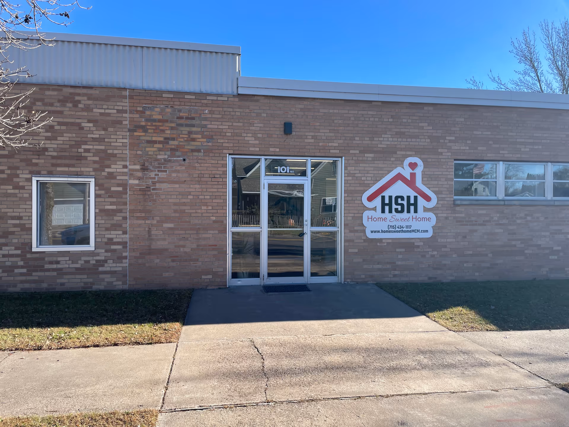 Brick facility with glass doors and a large Home Sweet Home sign at entrance.