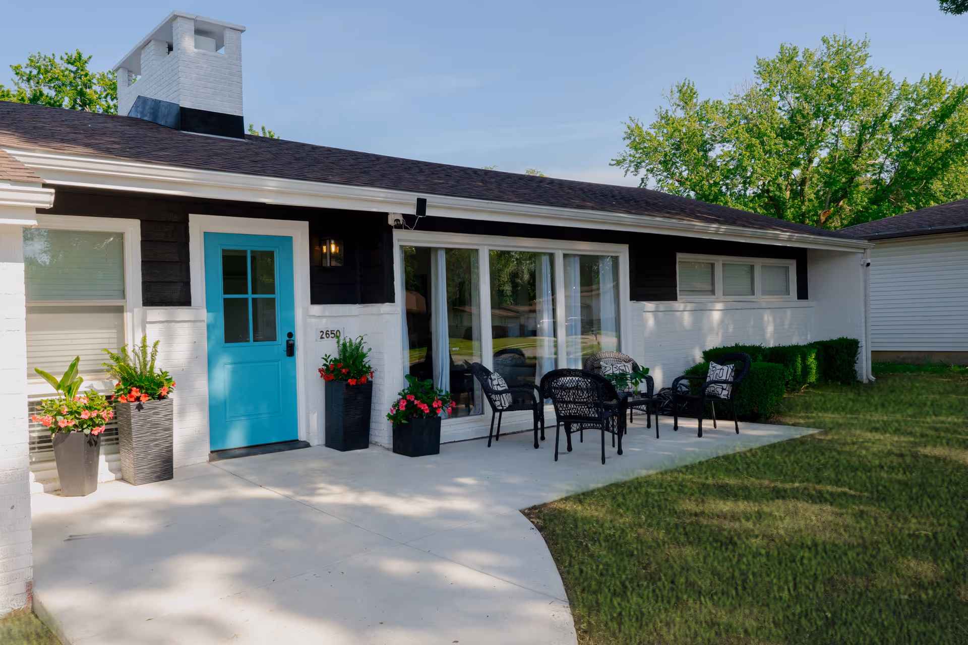 Front exterior of Cozy Cottage Senior Living with turquoise door and patio seating.