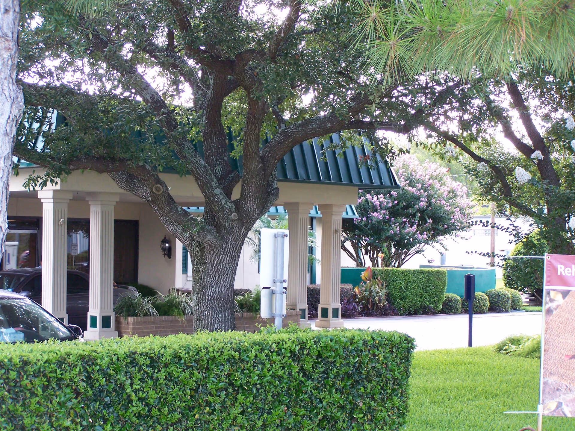 Senior living facility entrance with columns and lush green landscaping.