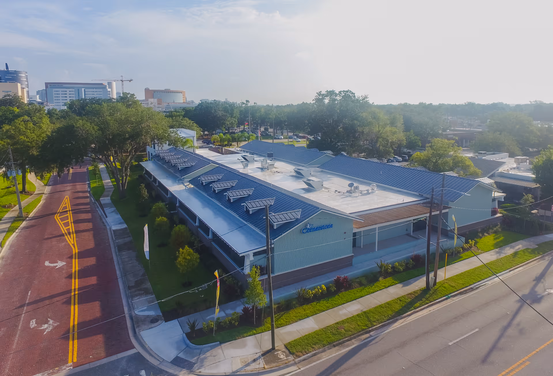 Aerial view of Cornerstone Hospice facility with blue roof, surrounded by trees and streets.
