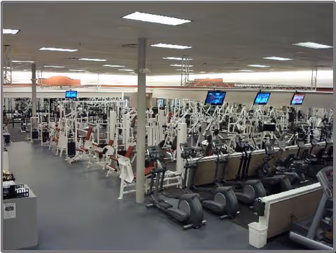 Interior view of a spacious gym with cardio and weight machines.