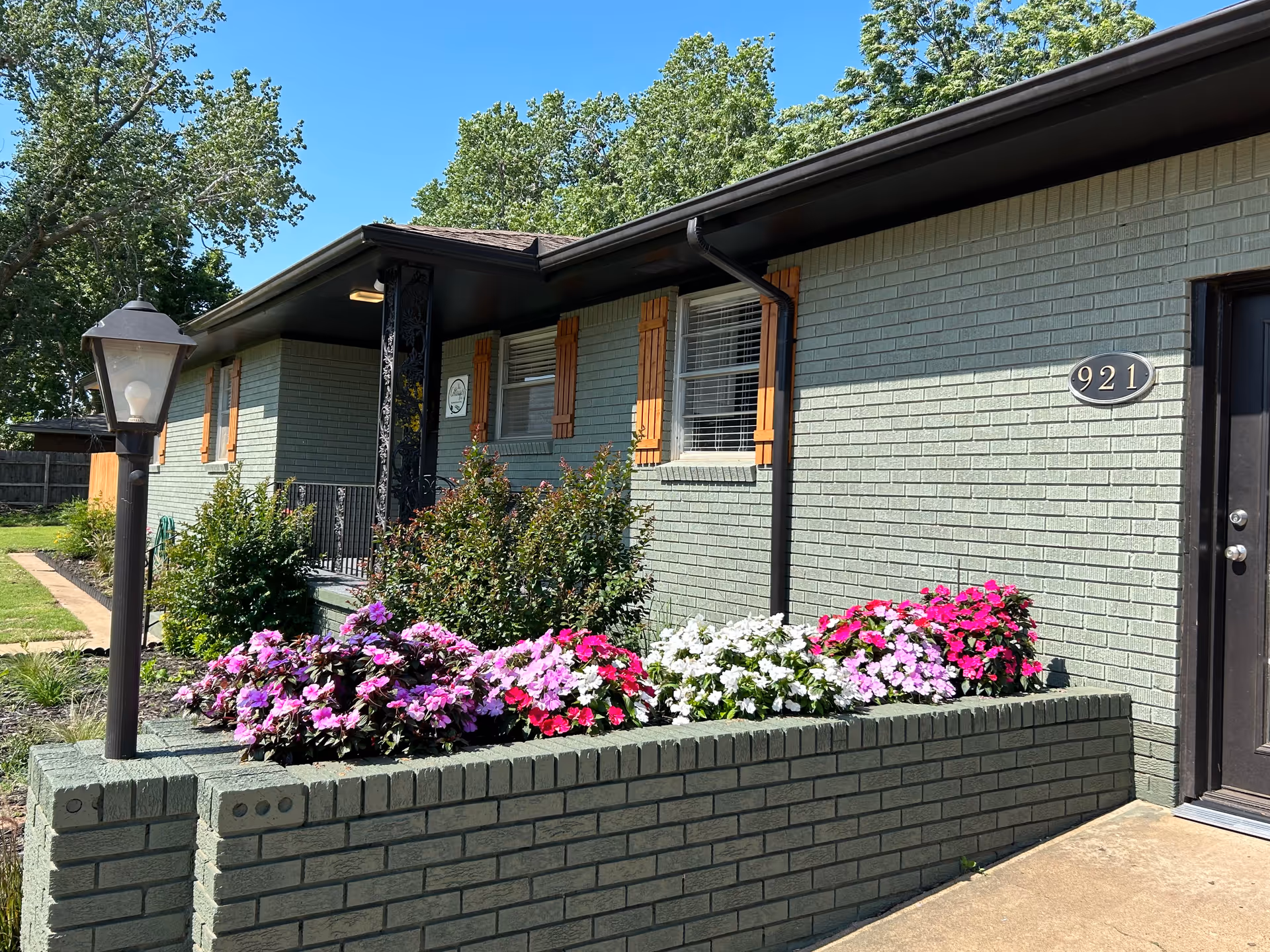 Single-story building exterior with a raised brick planter and colorful flowers by the entrance.