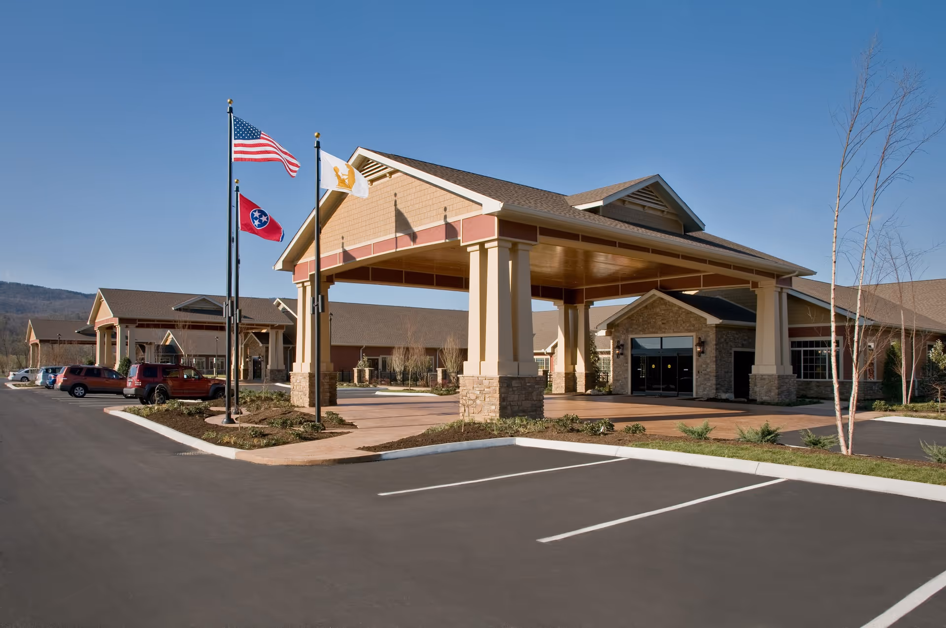 The Veranda at Rhea County front entrance with flags and a paved parking lot.