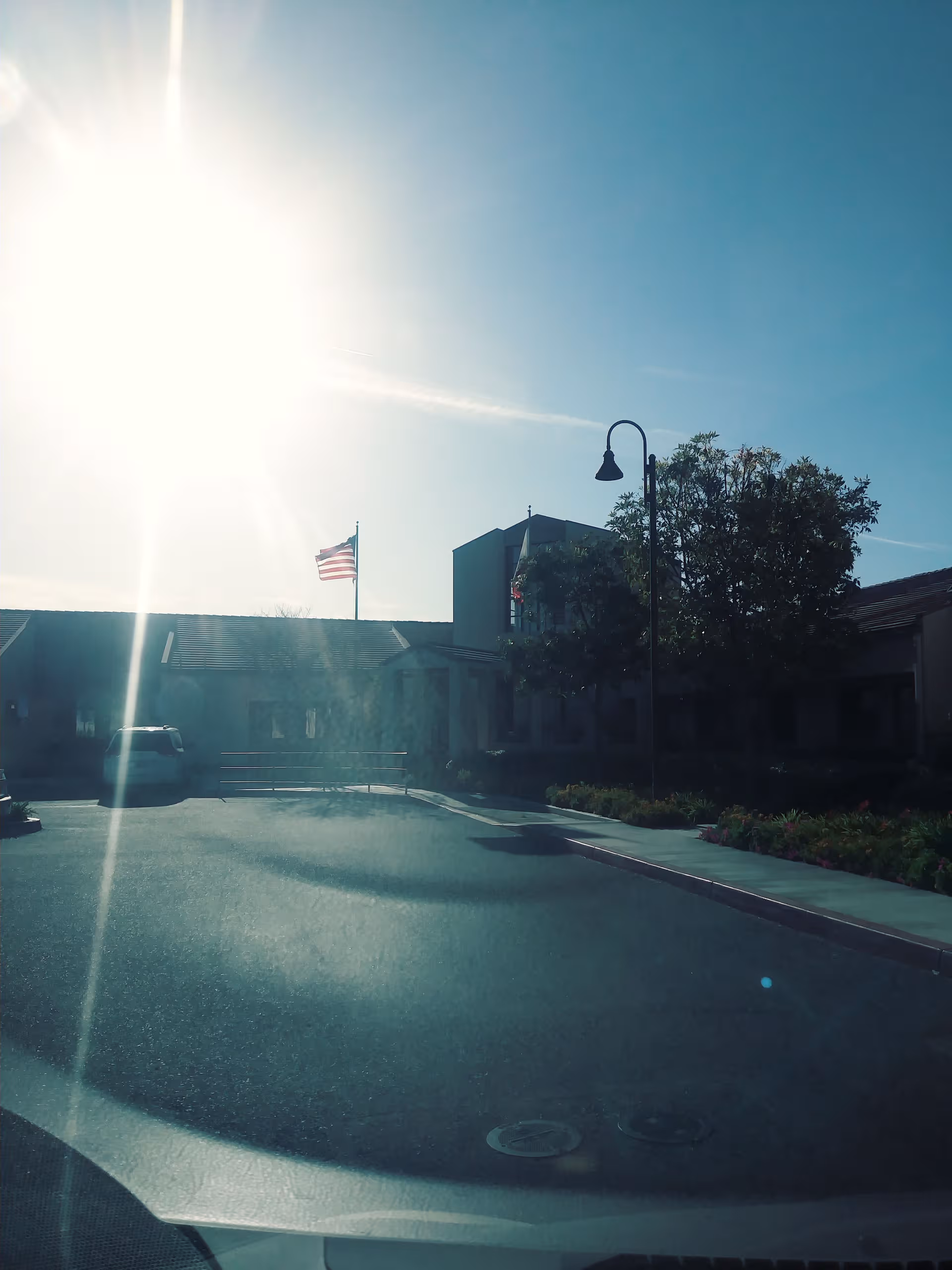 Front exterior of Walnut Village Orange County Retirement Community with flag, trees, and parking lot.