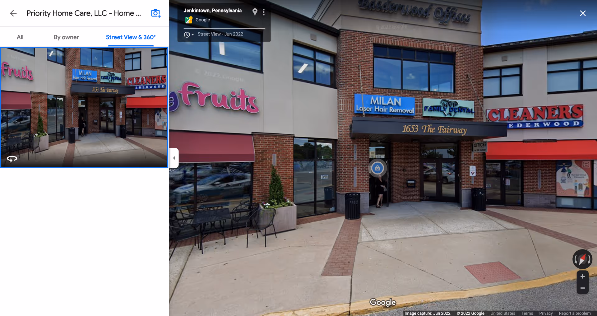 Exterior of a shopping plaza with brick storefronts, glass doors, and signs.